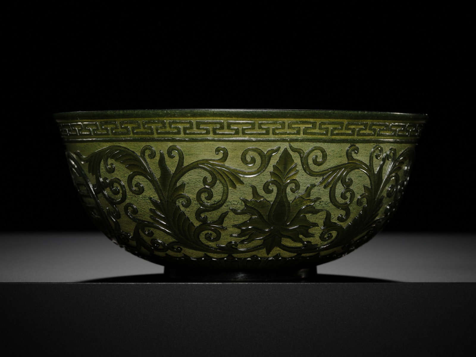 A MUGHAL-STYLE GREEN JADE 'LOTUS' BOWL, 18TH CENTURY: † A MUGHAL-STYLE GREEN JADE 'LOTUS' BOWL, 18TH CENTURY China, Qing dynasty. The thin rounded sides rising elegantly from a straight ring foot to a slightly everted rim, well-carved in shallow re