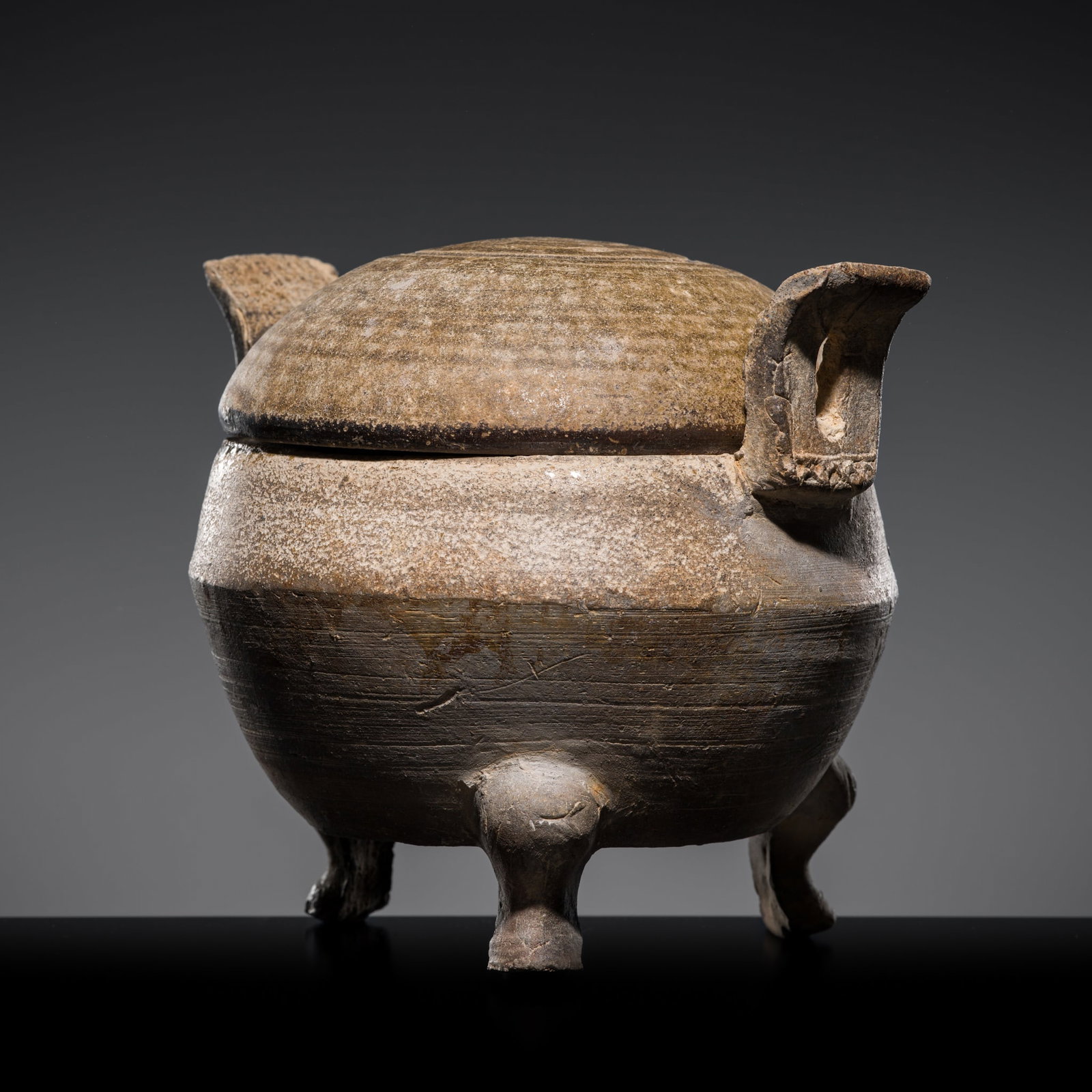AN ASH-GLAZED 'PROTO-PORCELAIN' RITUAL FOOD VESSEL AND COVER, DING, WARRING STATES TO WESTERN HAN: AN ASH-GLAZED 'PROTO-PORCELAIN' RITUAL FOOD VESSEL AND COVER, DING, WARRING STATES TO WESTERN HAN DYNASTY China, circa 3rd-2nd century BC. The plain globular body is raised on three cabriole legs, fla