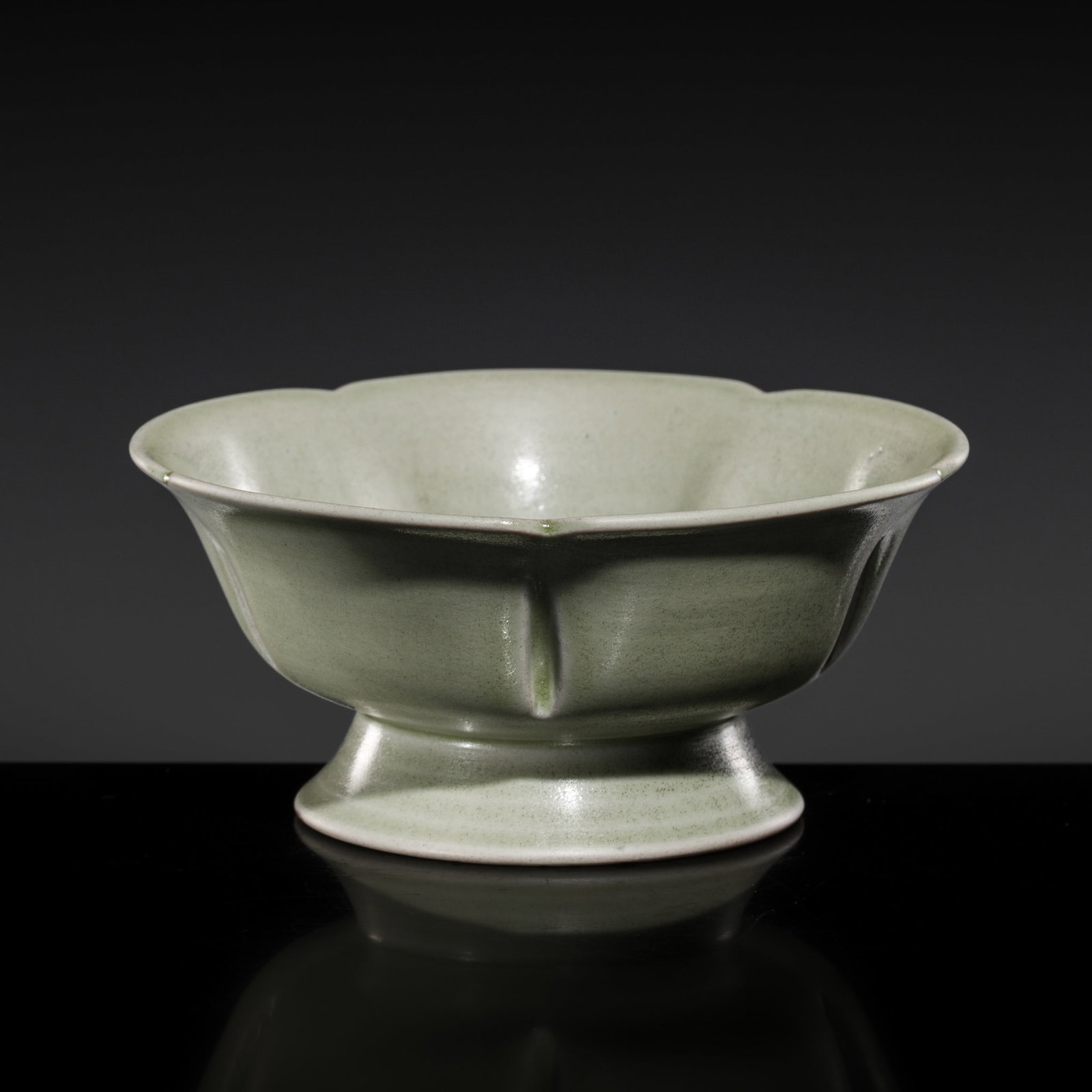A YUE LOBED CUP, FIVE DYNASTIES: A YUE LOBED CUP, FIVE DYNASTIES China. 907-960. The petal lobed body rising from a spreading foot to a foliate rim, the sides with five indentations to separate the petals, and covered overall in a pa