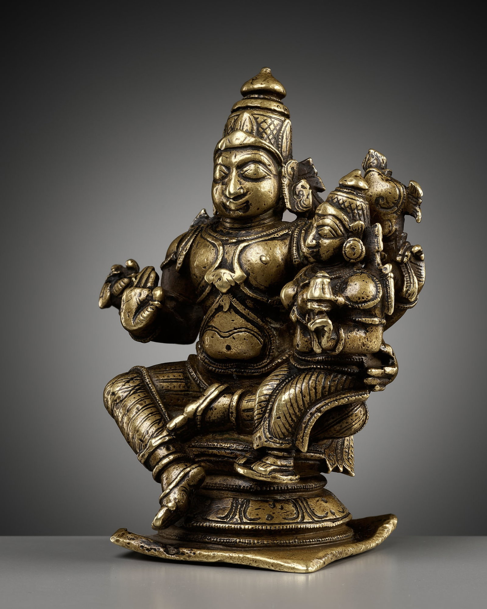 A BRONZE FIGURE OF VISHNU AND LAKSHMI, NAYAK PERIOD: A BRONZE FIGURE OF VISHNU AND LAKSHMI, NAYAK PERIOD South India, circa 17th century. The four-armed deity cast seated in lalitasana on a beaded double lotus base, the secondary arms holding his milita