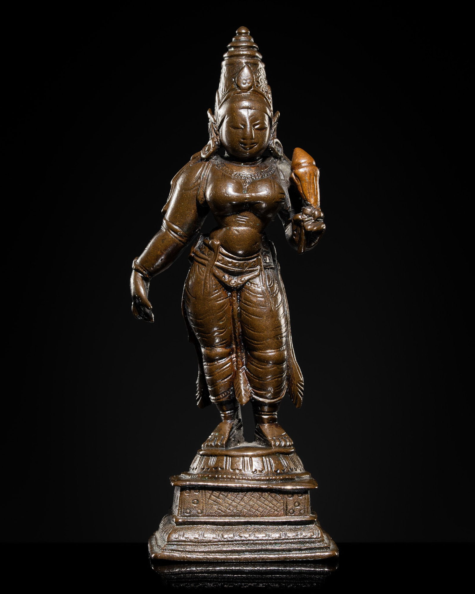 A COPPER-INLAID BRONZE FIGURE OF SRI DEVI, SOUTH INDIA, 17TH-18TH CENTURY: A COPPER-INLAID BRONZE FIGURE OF SRI DEVI, SOUTH INDIA, 17TH-18TH CENTURY Finely cast, standing in tribhanga on a lotus pedestal set upon a stepped square plinth. The consort of Vishnu holding a lotus