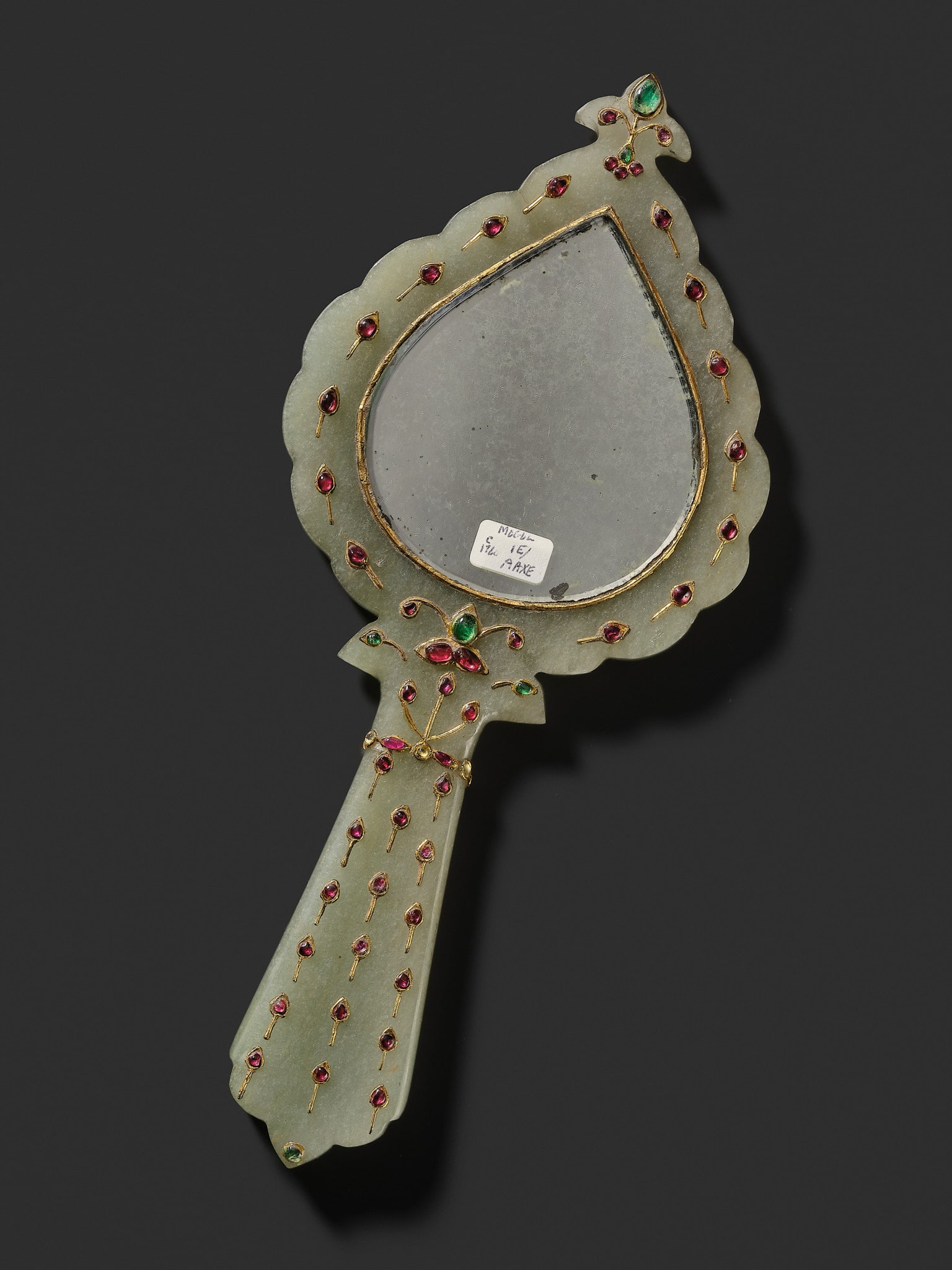 A MUGHAL GEM-SET AND GOLD-INLAID JADE HAND MIRROR, INDIA, 18TH-19TH CENTURY: A MUGHAL GEM-SET AND GOLD-INLAID JADE HAND MIRROR, INDIA, 18TH-19TH CENTURY Of tear-drop form fitted with a flaring handle and surmounted by a trefoil terminal, finely decorated with floral arabesques