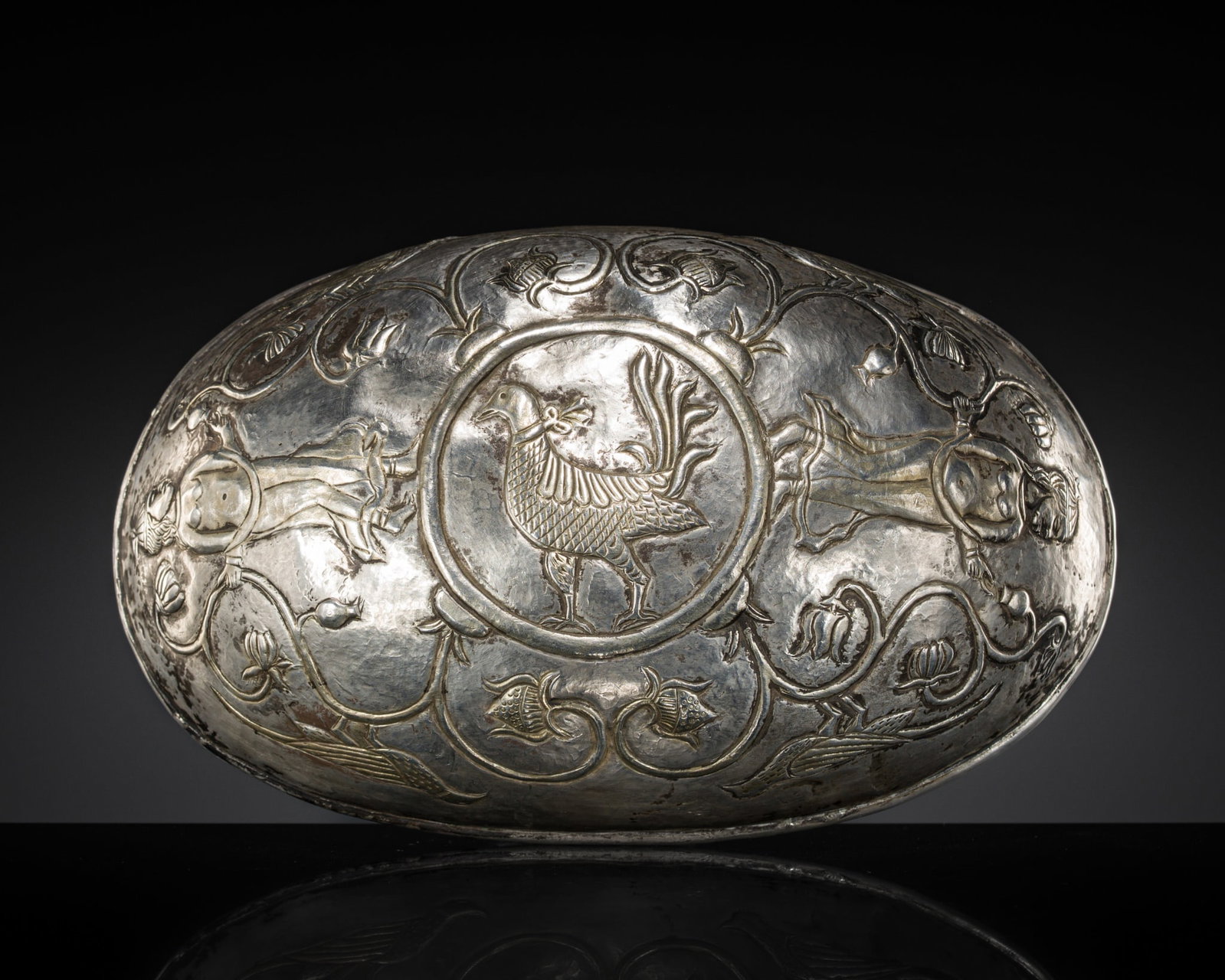 A FINE SILVER REPOUSSÉ 'NUDE MAIDENS' BOWL, SASANIAN DYNASTY, CIRCA 5TH-7TH CENTURY: A FINE SILVER REPOUSSÉ 'NUDE MAIDENS' BOWL, SASANIAN DYNASTY, CIRCA 5TH-7TH CENTURY Of elliptical form, finely chased to depict a central medallion enclosing a bird with splayed tail feathers, a 