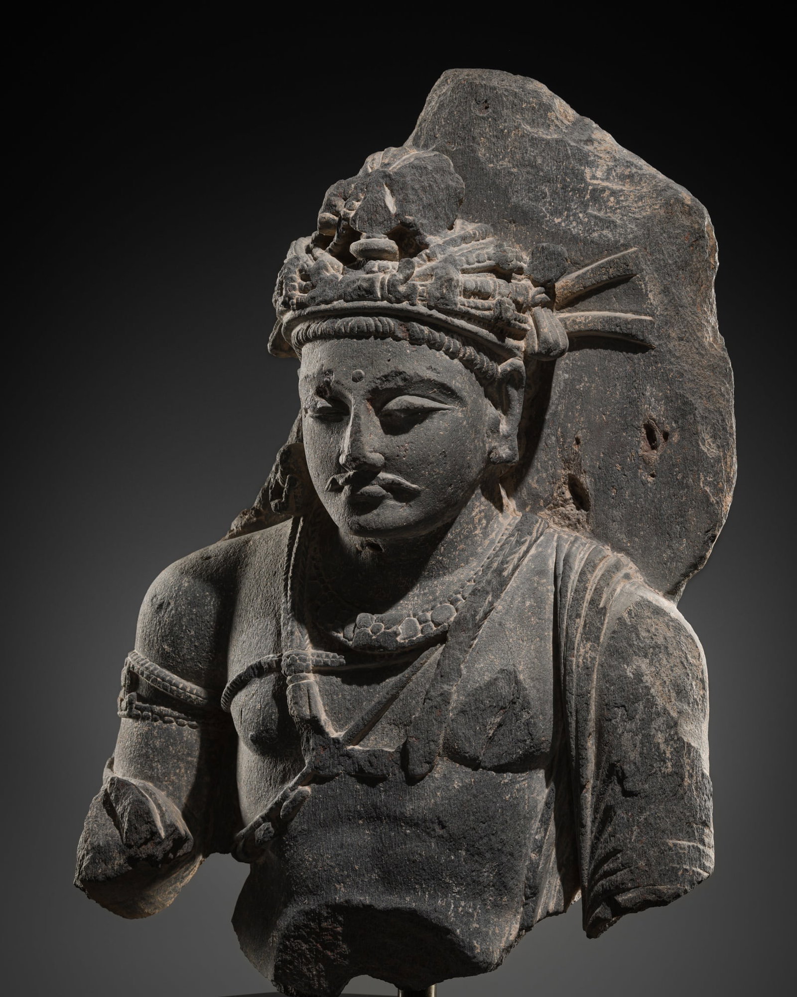 A GRAY SCHIST BUST OF BODHISATTVA SHAKYAMUNI, ANCIENT REGION OF GANDHARA, 2ND-3RD CENTURY: A GRAY SCHIST BUST OF BODHISATTVA SHAKYAMUNI, ANCIENT REGION OF GANDHARA, 2ND-3RD CENTURY Kushan period. Well-carved, his robe elegantly draped across his left shoulder, wearing multiple necklaces