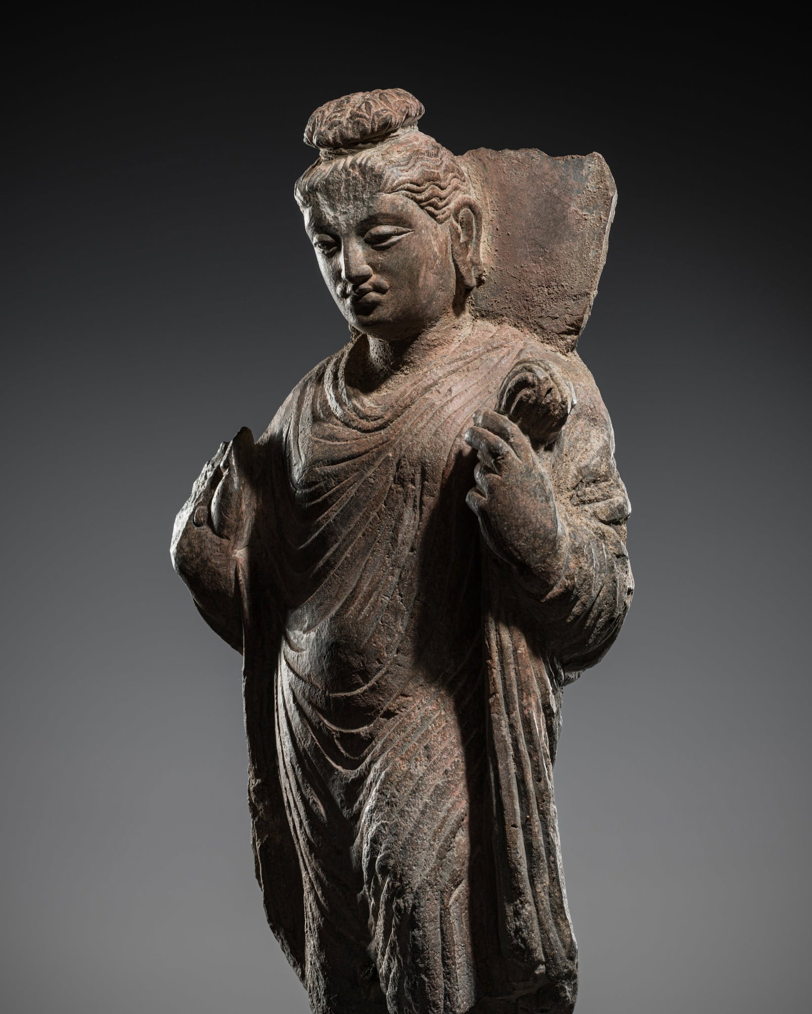 A GRAY SCHIST FIGURE OF BUDDHA, ANCIENT REGION OF GANDHARA, 3RD-4TH CENTURY: A GRAY SCHIST FIGURE OF BUDDHA, ANCIENT REGION OF GANDHARA, 3RD-4TH CENTURY A gently modeled example of Gandharan Buddhist sculpture, this figure displays the region's characteristic stylistic