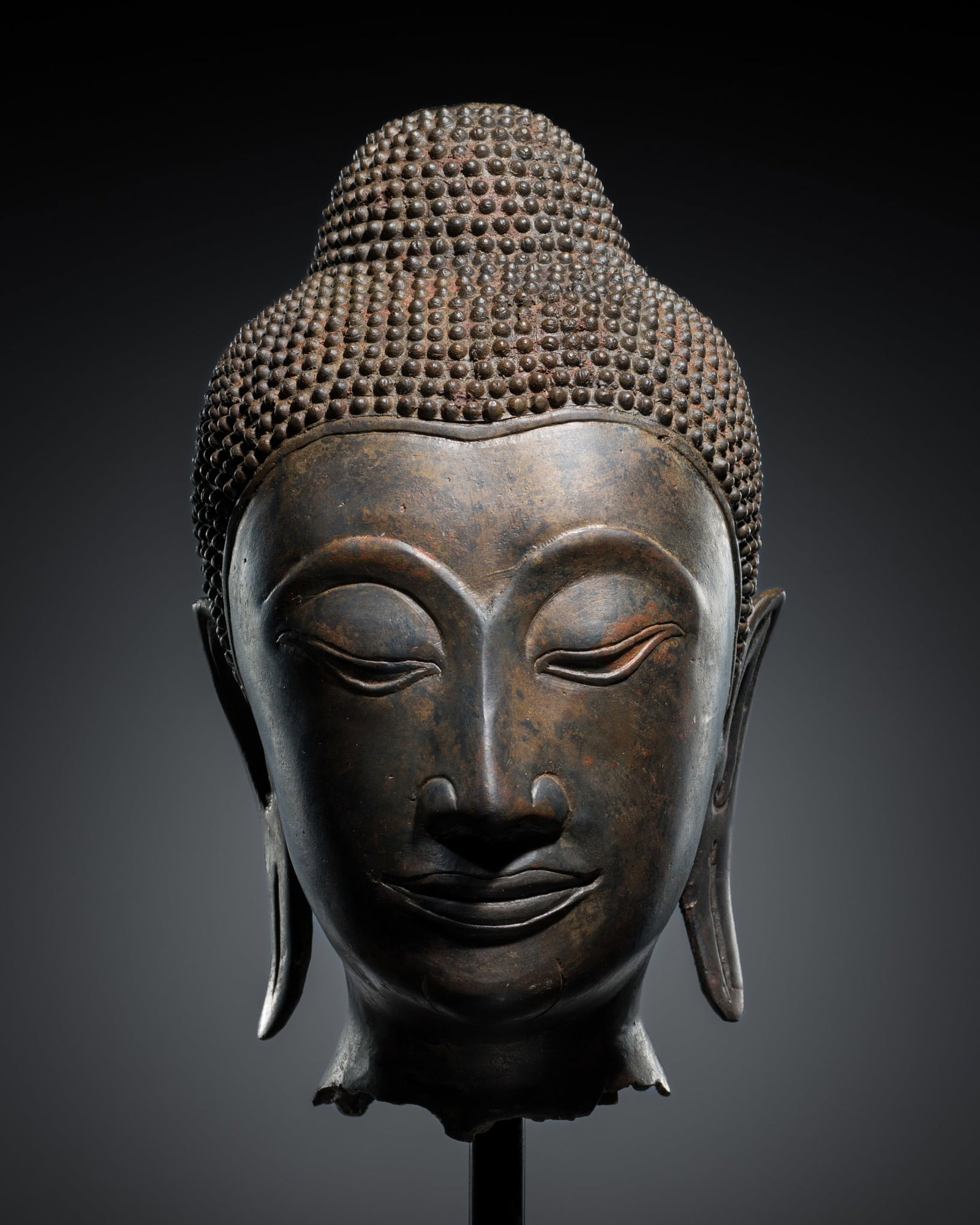 A FINE BRONZE HEAD OF BUDDHA, AYUTTHAYA PERIOD, 16TH-17TH CENTURY: A FINE BRONZE HEAD OF BUDDHA, AYUTTHAYA PERIOD, 16TH-17TH CENTURY Thailand. Heavily cast, the exquisitely modeled face with a serene expression, deep heavy-lidded eyes, elegantly arched brows, neatly 