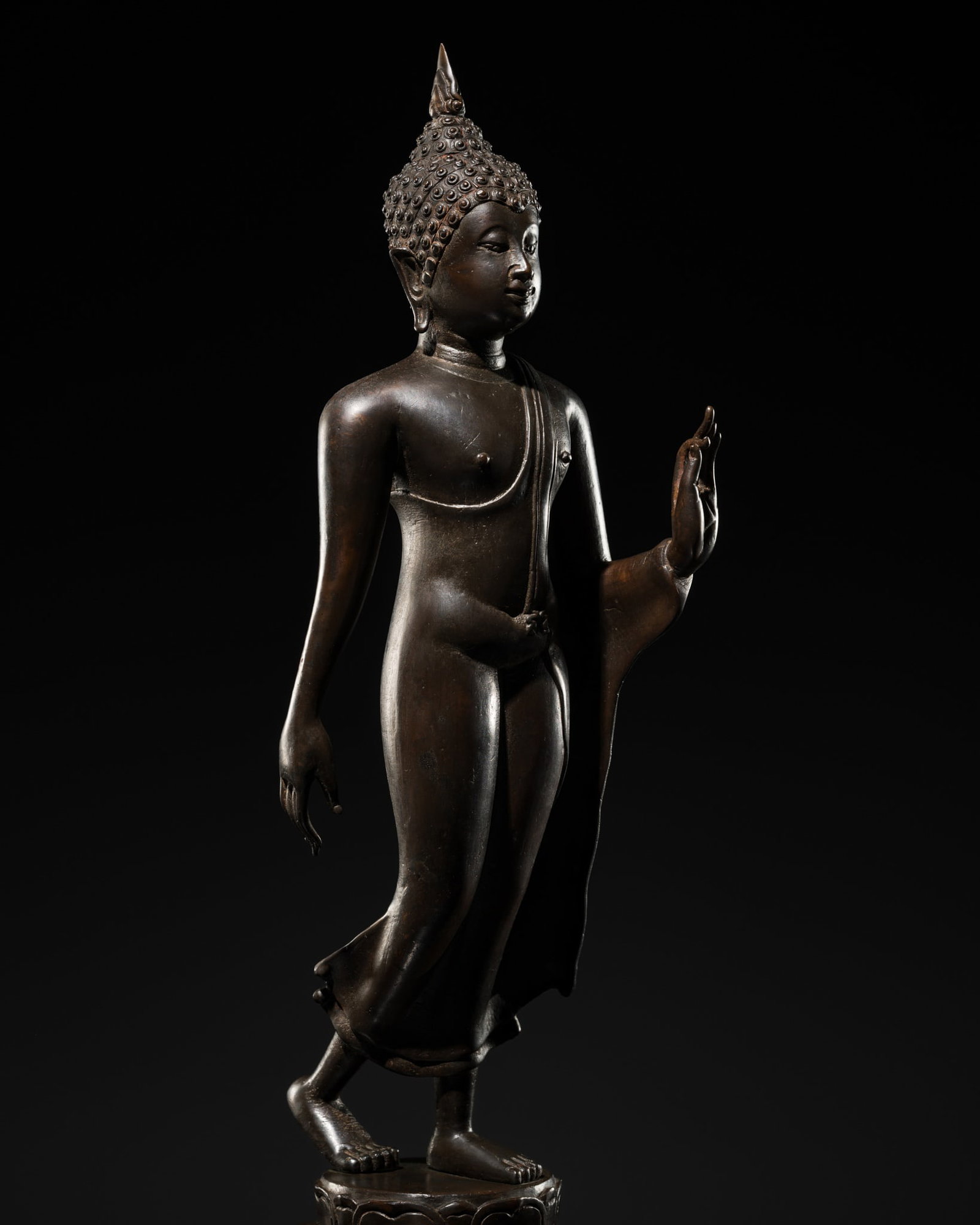 A FINE SUKHOTHAI STYLE BRONZE FIGURE OF THE WALKING BUDDHA, 18TH-19TH CENTURY: † A FINE SUKHOTHAI STYLE BRONZE FIGURE OF THE WALKING BUDDHA, 18TH-19TH CENTURY Thailand. Superbly cast striding with the right leg slightly bent, standing atop a square base with circular lotus