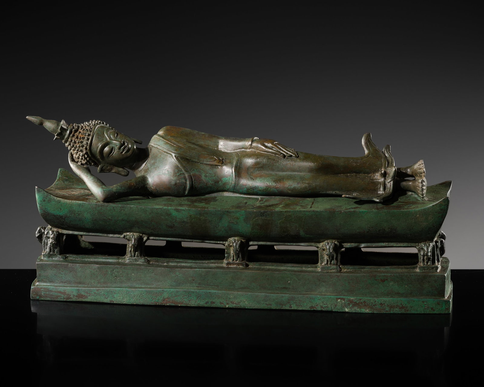 A BRONZE FIGURE OF BUDDHA IN PARINIRVANA, THAILAND, 19TH-20TH CENTURY: A BRONZE FIGURE OF BUDDHA IN PARINIRVANA, THAILAND, 19TH-20TH CENTURY Finely cast, the Buddha lying on his right side with his hand supporting his head over a separately cast openworked stepped base w