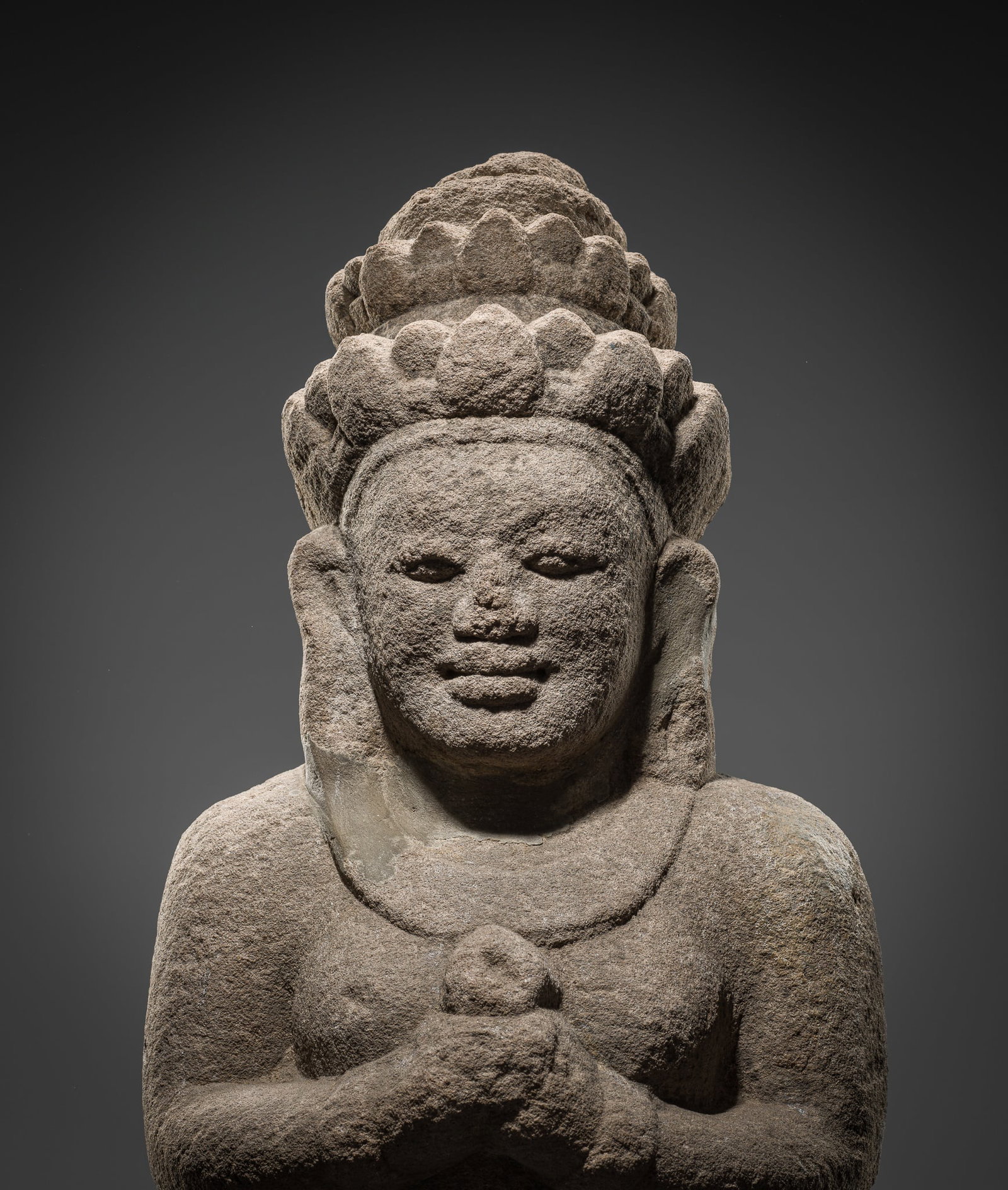 A SANDSTONE 'APSARA' BRACKET, CHAMPA, 10TH CENTURY: A SANDSTONE 'APSARA' BRACKET, CHAMPA, 10TH CENTURY Vietnam. This celestial being is a resident of heaven, ornamented as a goddess with tiered crown, heavy earrings, and broad necklace. She reverently 