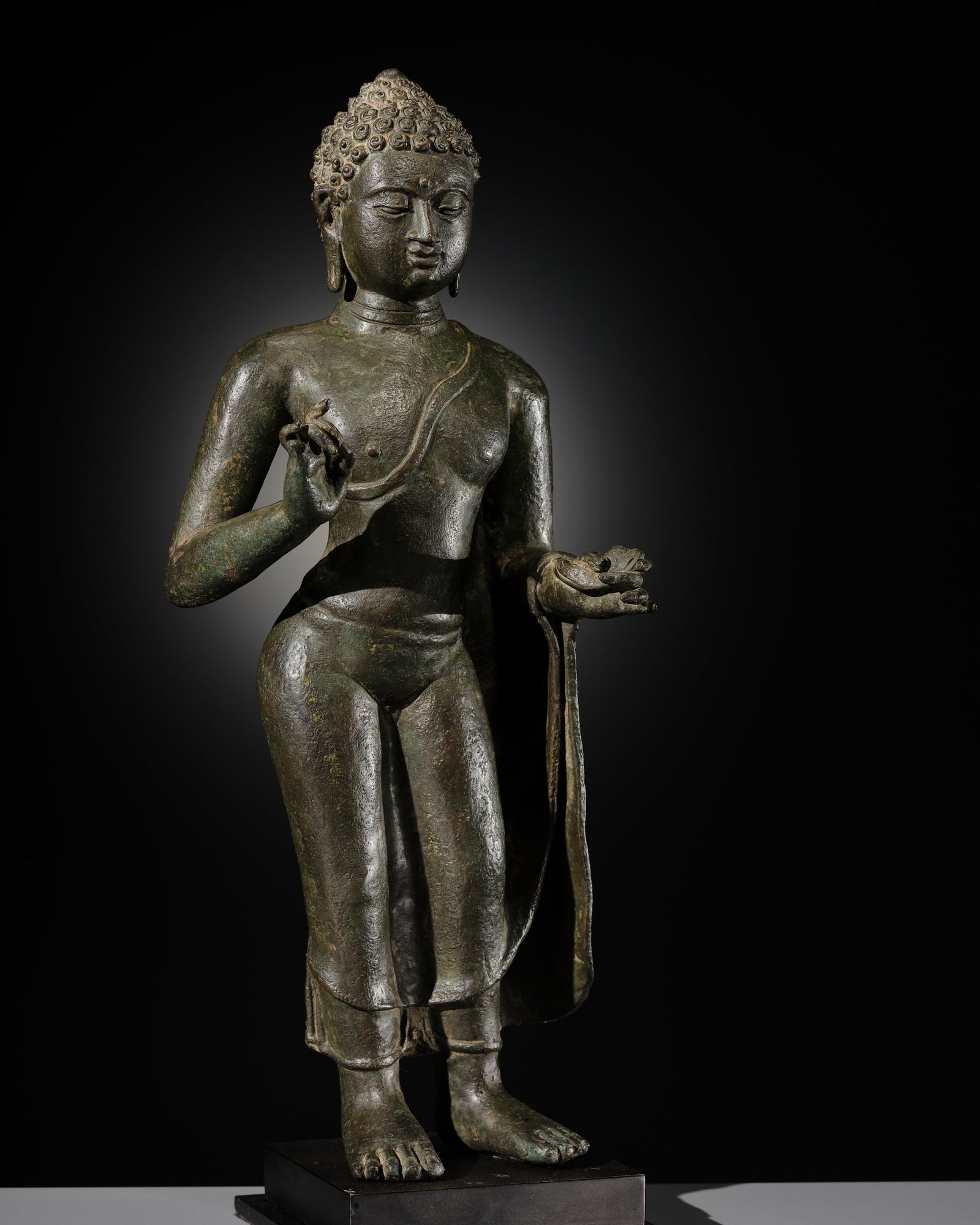 A BRONZE FIGURE OF BUDDHA, CENTRAL JAVA, 8TH-10TH CENTURY: A BRONZE FIGURE OF BUDDHA, CENTRAL JAVA, 8TH-10TH CENTURY Indonesia. Expertly cast, standing in samabhanga with the arms extended, the right hand held in karana mudra and the left hand grasping the he