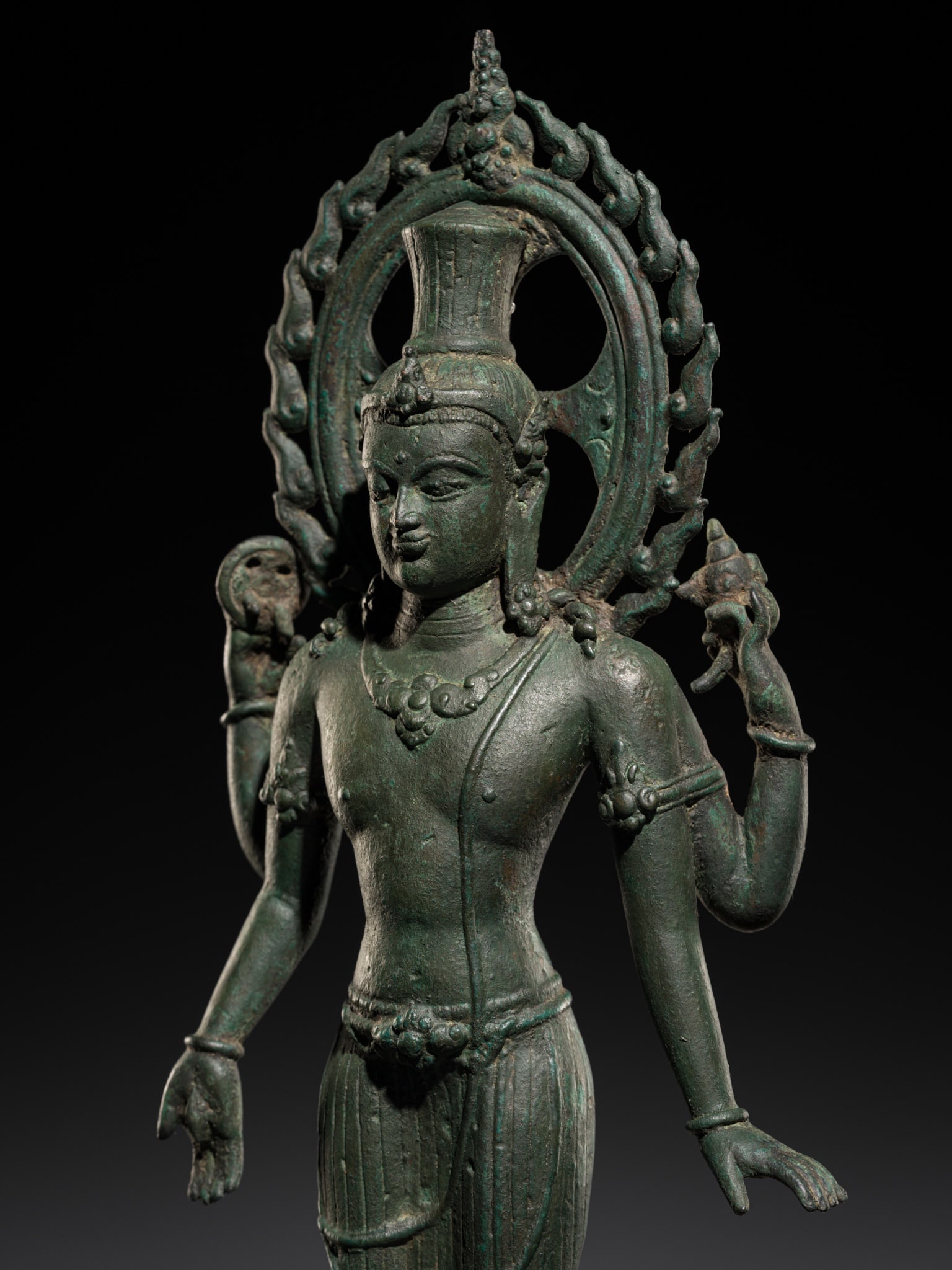 A LARGE BRONZE FIGURE OF VISHNU WITH FLAMING HALO, CENTRAL JAVA, 9TH-10TH CENTURY: A LARGE BRONZE FIGURE OF VISHNU WITH FLAMING HALO, CENTRAL JAVA, 9TH-10TH CENTURY Indonesia. Finely cast, standing in samapada, the primary right hand held in varada mudra, the secondary arms raised a