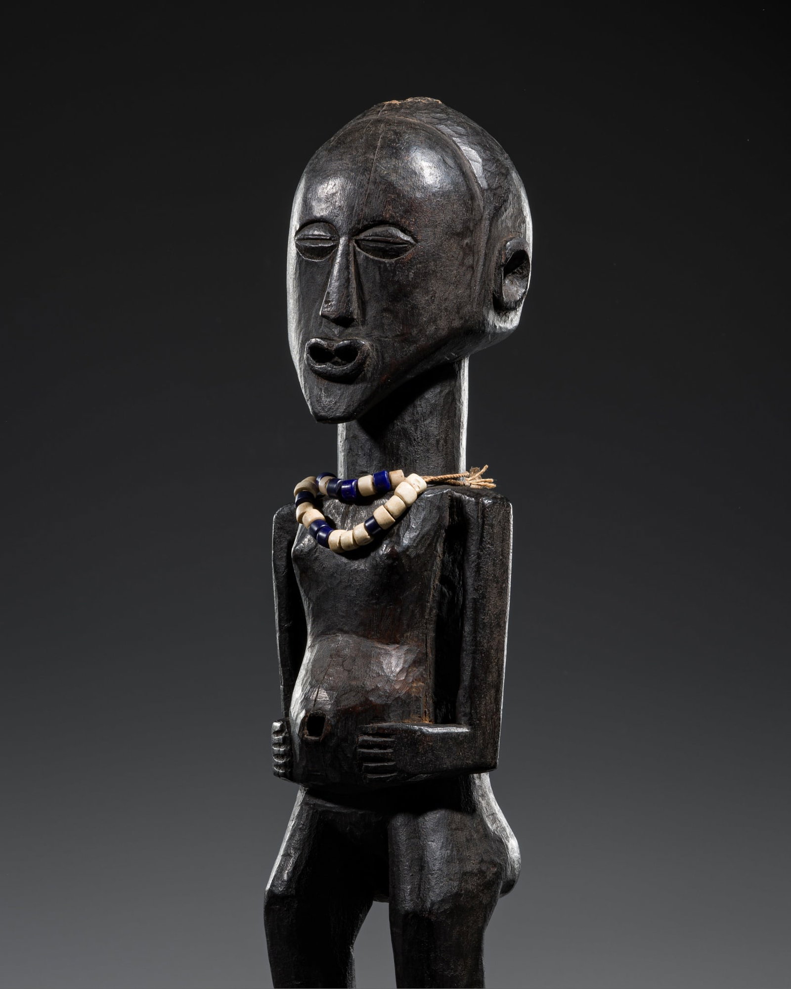 A NSAPO WOOD POWER FIGURE, LATE 19TH-EARLY 20TH CENTURY: A NSAPO WOOD POWER FIGURE, LATE 19TH-EARLY 20TH CENTURY Democratic Republic of the Congo. Boldly carved, standing in a classic Buanga posture, with flat feet, slightly flexed legs, and pronounced butt