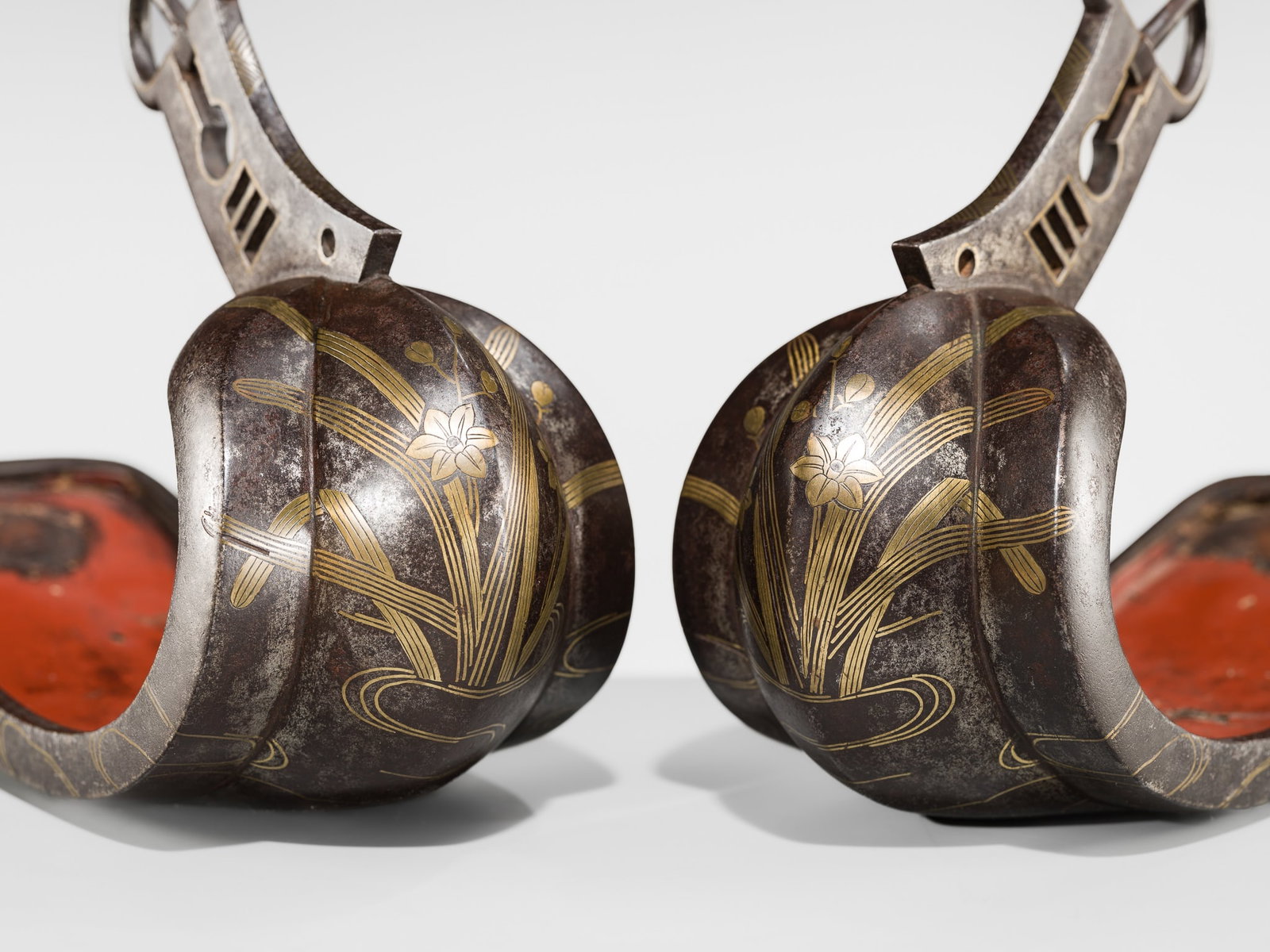 A FINE PAIR OF INLAID AND LACQUERED IRON STIRRUPS (ABUMI): A FINE PAIR OF INLAID AND LACQUERED IRON STIRRUPS (ABUMI) Japan, 17th-18th century, Edo period (1615-1868) Of typical form, the exteriors finely decorated in gilt metal with flowering narcissus