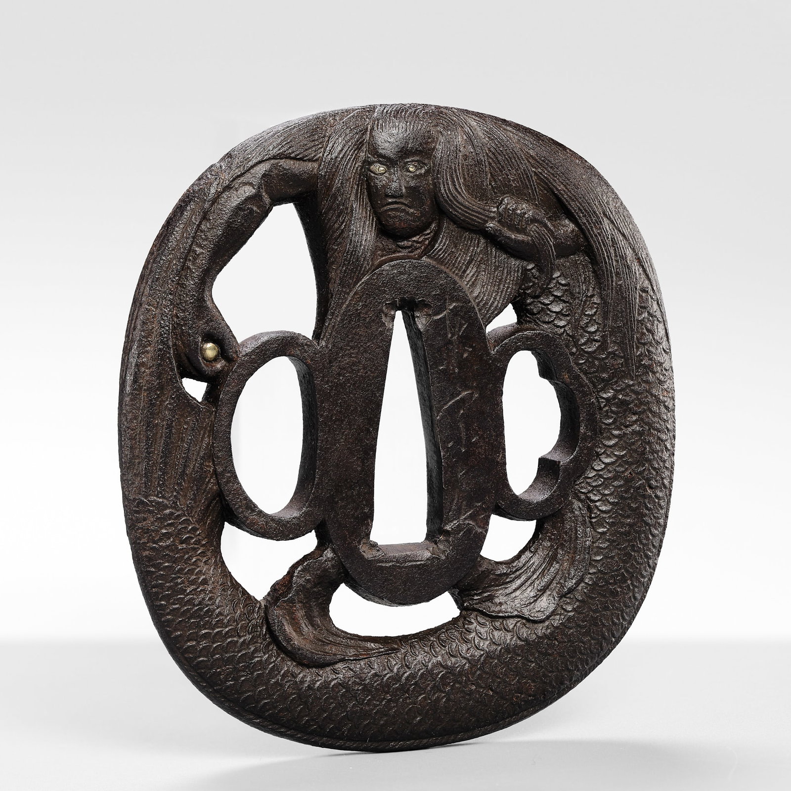AZUMA MUNEHARU: A RARE IRON SUKASHI TSUBA OF A NINGYO (MERMAID) HOLDING A TAMA: AZUMA MUNEHARU: A RARE IRON SUKASHI TSUBA OF A NINGYO (MERMAID) HOLDING A TAMA By Azuma Muneharu, signed Azuma Muneharu Japan, 18th century, Edo period (1615-1868) Published & Exhibited:</