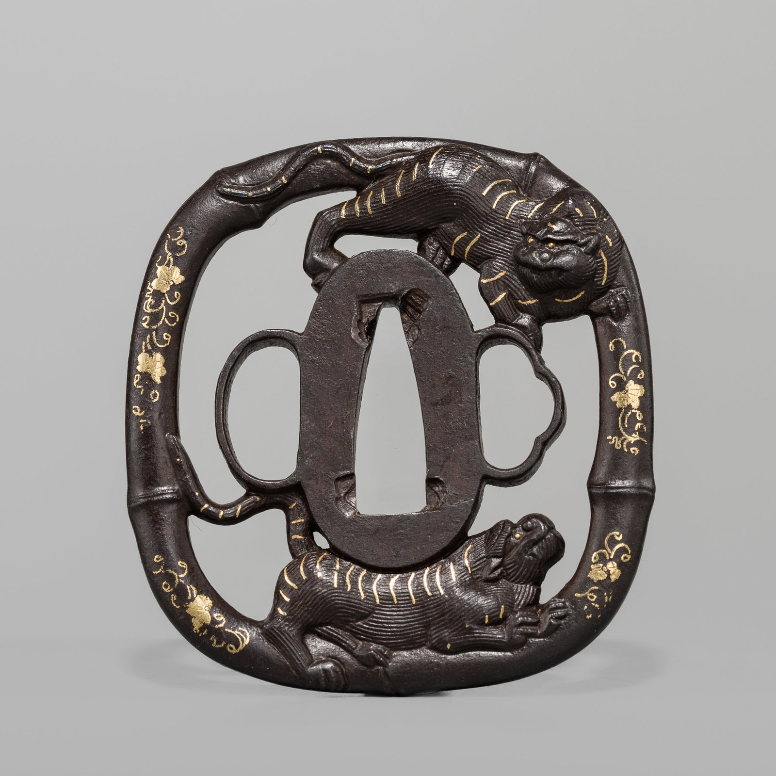 A SHOAMI SCHOOL IRON SUKASHI TSUBA WITH TIGERS AND BAMBOO: A SHOAMI SCHOOL IRON SUKASHI TSUBA WITH TIGERS AND BAMBOO Unsigned Japan, late 18th to early 19th century, Edo period (1615-1868) Of kawarigata form, with one kozuka and kogai hitsu ana, ca