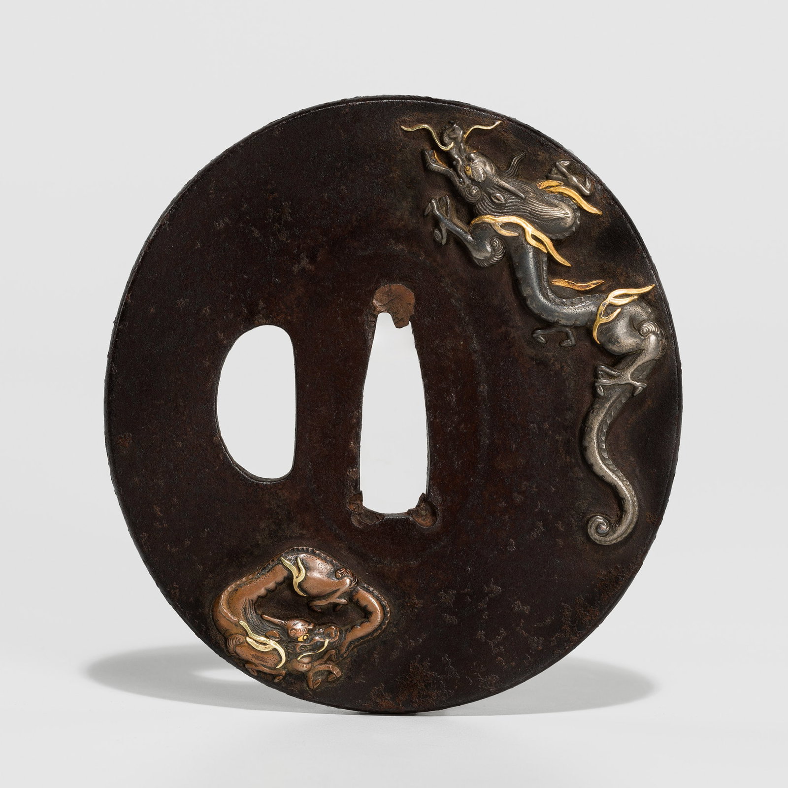 IWAMOTO MUNEGAGA: A FINE IRON TSUBA DEPICTING TWO DRAGONS: IWAMOTO MUNEGAGA: A FINE IRON TSUBA DEPICTING TWO DRAGONS By Iwamoto Munegaga, signed Iwamoto Munegaga with kakihan Japan, early 19th century, Edo period (1615-1868) Of naga-marugata shape with a squa