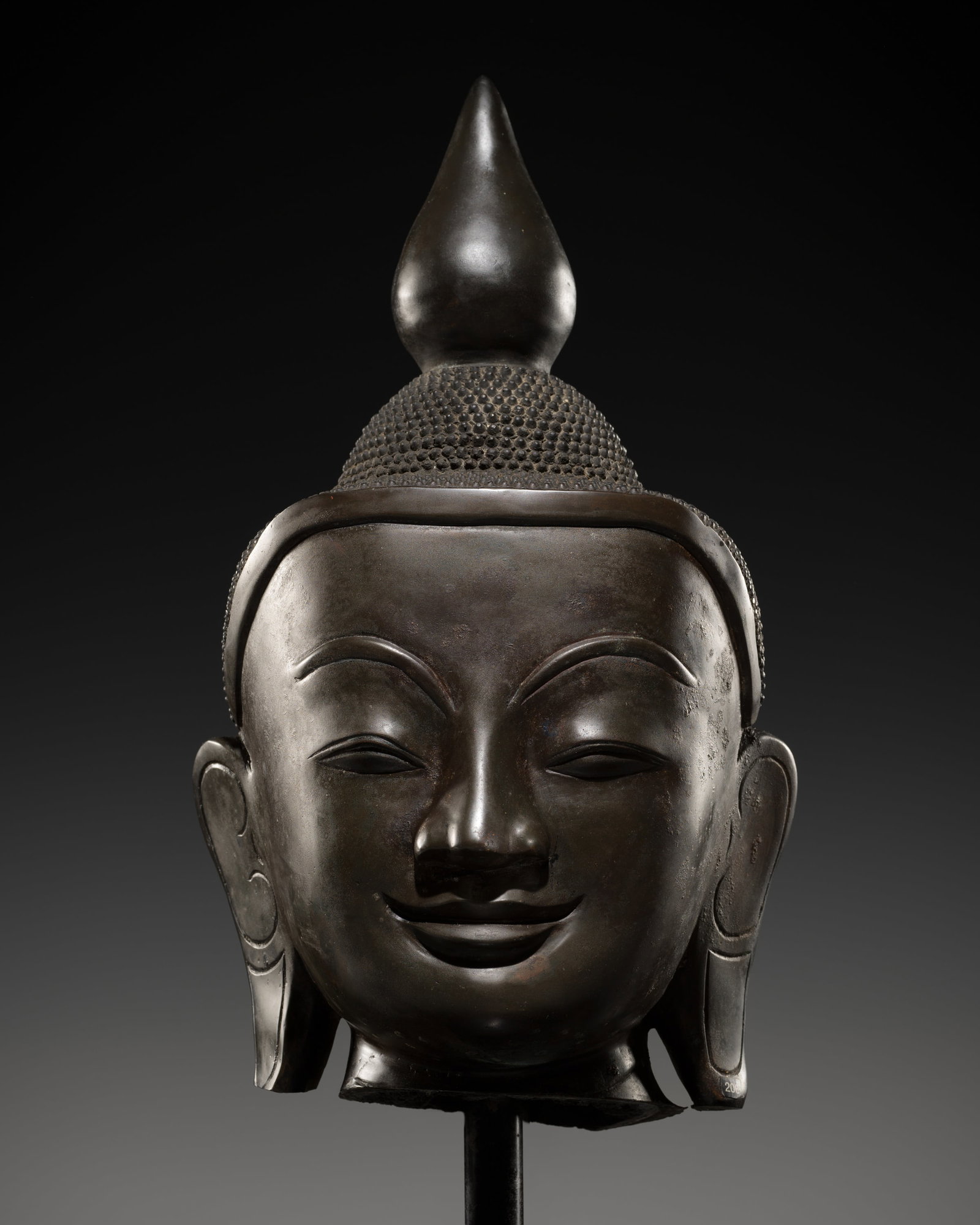 A MONUMENTAL BRONZE HEAD OF BUDDHA SHAKYAMUNI, AVA PERIOD, 17TH CENTURY: A MONUMENTAL BRONZE HEAD OF BUDDHA SHAKYAMUNI, AVA PERIOD, 17TH CENTURY This lot is from a single owner collection and is therefore offered without reserve The Jorgen Ruben Gallery Ledger, entry from 