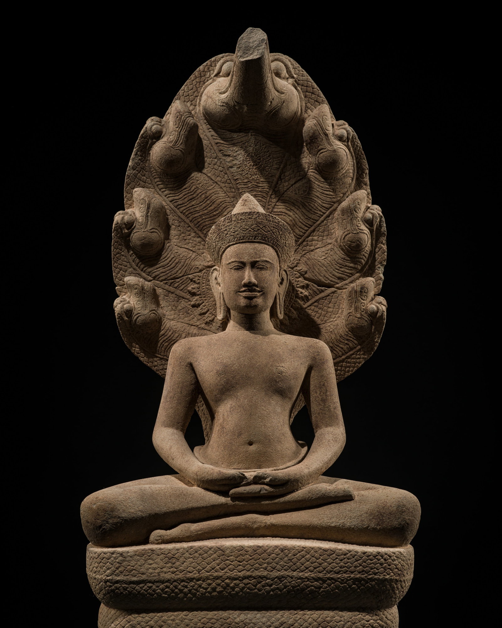 A LARGE SANDSTONE FIGURE OF BUDDHA MUCHALINDA, ANGKOR WAT STYLE, 12TH CENTURY: A LARGE SANDSTONE FIGURE OF BUDDHA MUCHALINDA, ANGKOR WAT STYLE, 12TH CENTURY This lot is from a single owner collection and is therefore offered without reserve The Jorgen Ruben Gallery Ledger, entry
