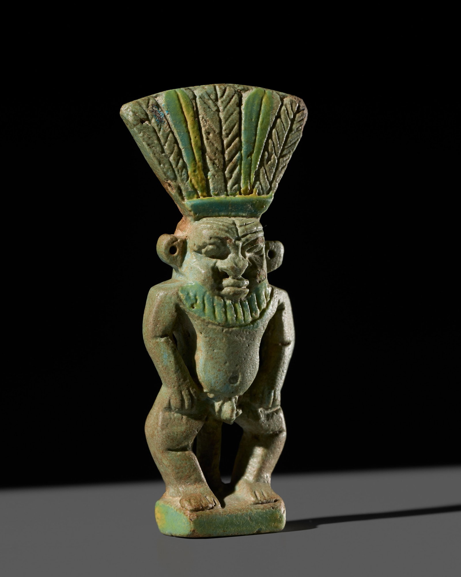 AN EGYPTIAN TURQUOISE FAIENCE 'BES' AMULET, THIRD INTERMEDIATE PERIOD (1 of 15)