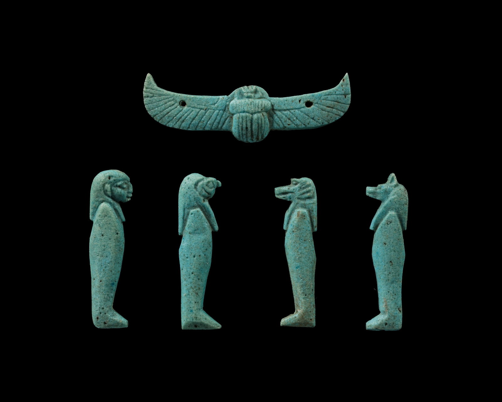 A COMPLETE SET OF TURQUOISE-GLAZED FAIENCE AMULETS OF THE FOUR SONS OF HORUS AND A WING SCARAB,: A COMPLETE SET OF TURQUOISE-GLAZED FAIENCE AMULETS OF THE FOUR SONS OF HORUS AND A WING SCARAB, THIRD INTERMEDIATE PERIOD-LATE PERIOD This lot is from a single owner collection and is therefore offere
