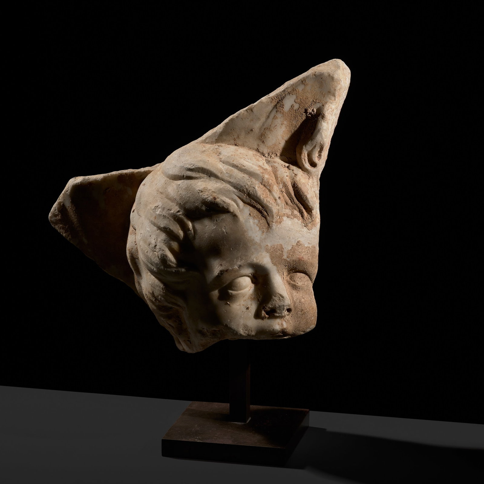 A ROMAN MARBLE SARCOPHAGUS FRAGMENT WITH CUPID, CIRCA 1ST CENTURY AD: A ROMAN MARBLE SARCOPHAGUS FRAGMENT WITH CUPID, CIRCA 1ST CENTURY AD This lot is from a single owner collection and is therefore offered without reserve The young god with a cherubic oval face, his lu