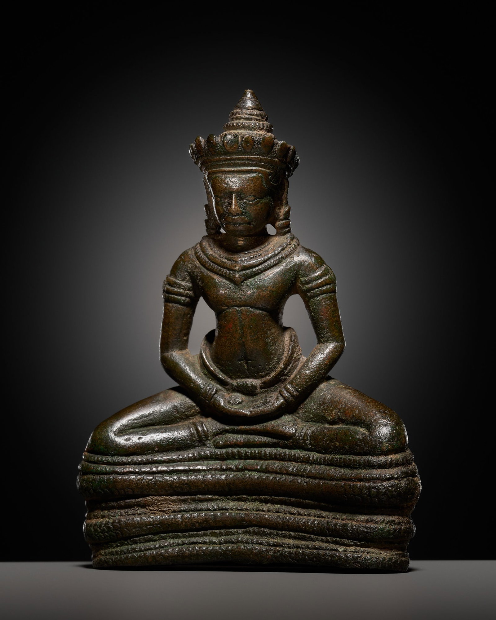 A RARE SMALL KHMER BRONZE FIGURE OF BUDDHA MUCHALINDA, ANGKOR WAT STYLE, 12TH-13TH CENTURY: A RARE SMALL KHMER BRONZE FIGURE OF BUDDHA MUCHALINDA, ANGKOR WAT STYLE, 12TH-13TH CENTURY This lot is from a single owner collection and is therefore offered without reserve The Jorgen Ruben Gallery 