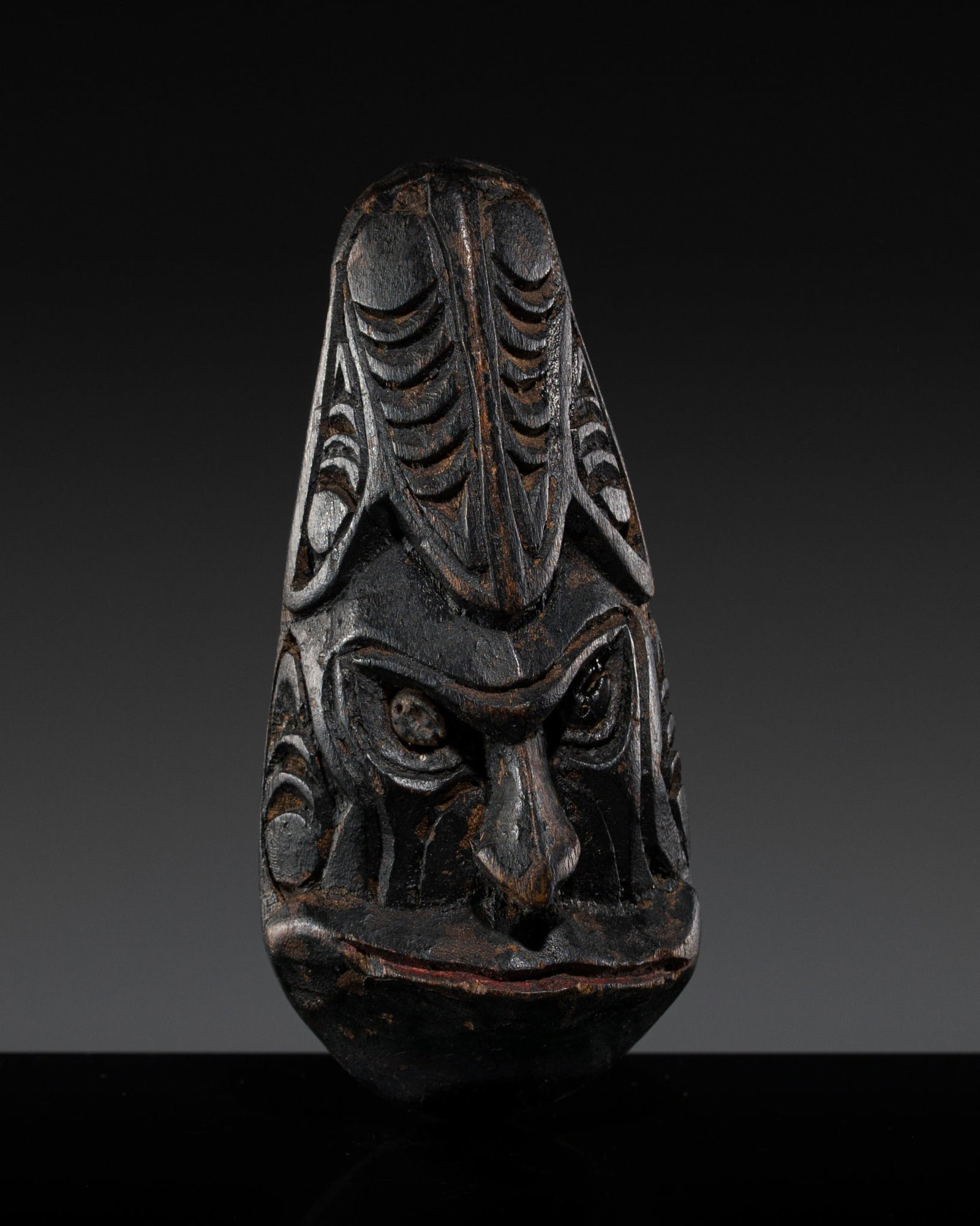 A DARK WOOD 'ANCESTOR'S MINIATURE HEAD' PENDANT, ASMAT PEOPLE: A DARK WOOD 'ANCESTOR'S MINIATURE HEAD' PENDANT, ASMAT PEOPLE This lot is from a single owner collection and is therefore offered without reserve Southwest Papua New Guinea, mid-20th century. Boldly c