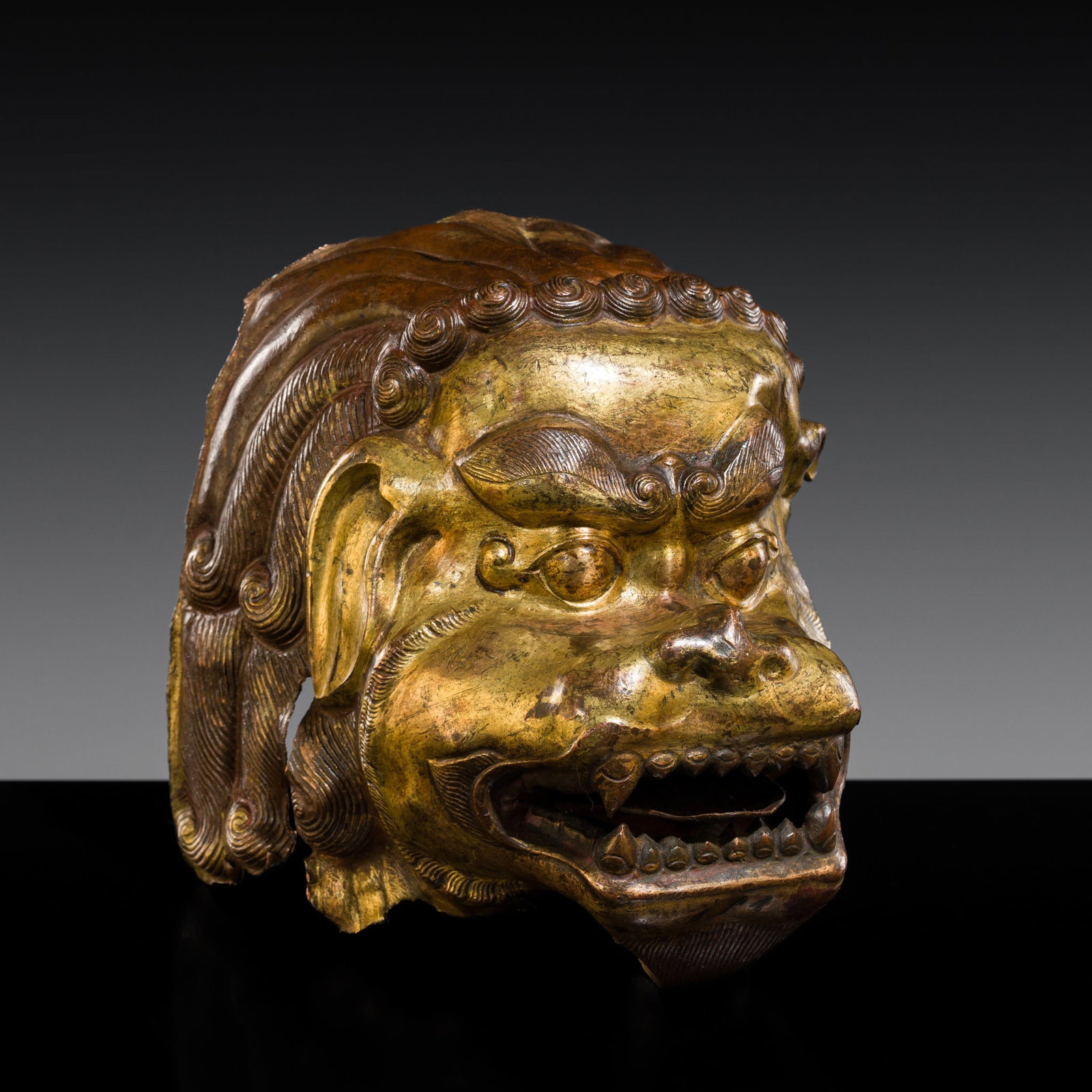 A GILT BRONZE REPOUSSÉ HEAD OF A SNOW LION, 16TH-17TH CENTURY: A GILT BRONZE REPOUSSÉ HEAD OF A SNOW LION, 16TH-17TH CENTURY This lot is from a single owner collection and is therefore offered without reserve Tibet. The fragmentary beast head with a fierce e