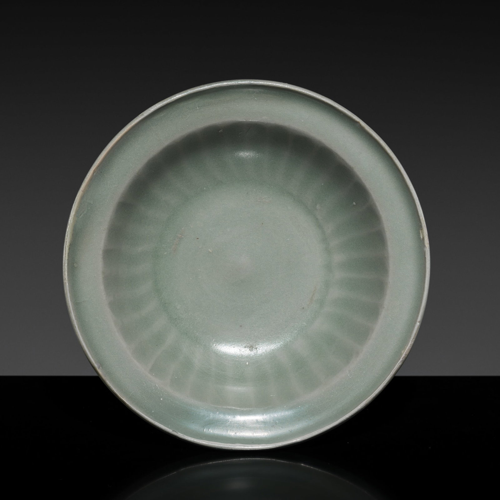 A SMALL CARVED LONGQUAN DISH, SOUTHERN SONG DYNASTY: A SMALL CARVED LONGQUAN DISH, SOUTHERN SONG DYNASTY This lot is from a single owner collection and is therefore offered without reserve China, 1125-1279. Well potted with shallow rounded sides support