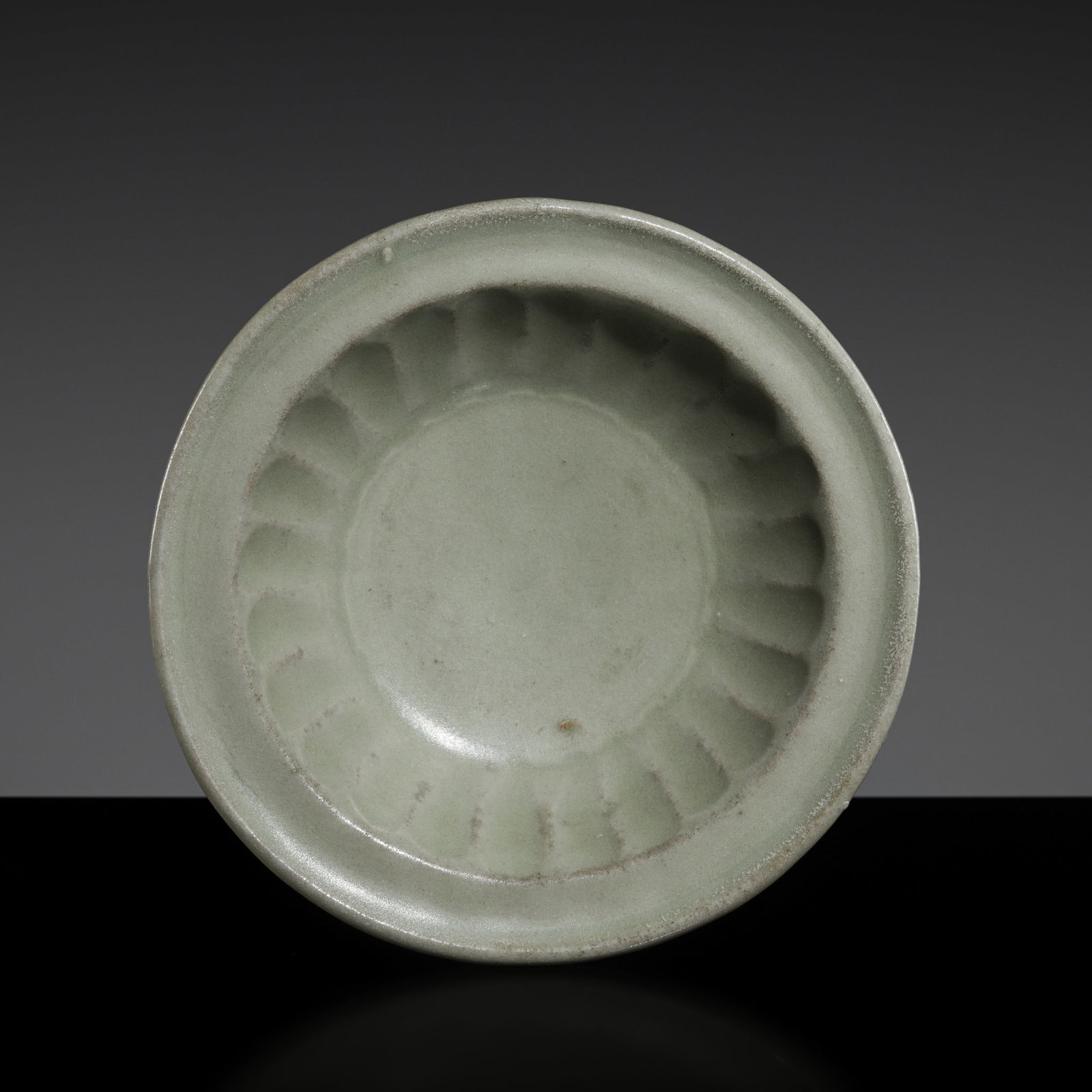 A SMALL CARVED LONGQUAN DISH, SOUTHERN SONG DYNASTY: A SMALL CARVED LONGQUAN DISH, SOUTHERN SONG DYNASTY This lot is from a single owner collection and is therefore offered without reserve China, 1125-1279. Well potted with shallow rounded sides support