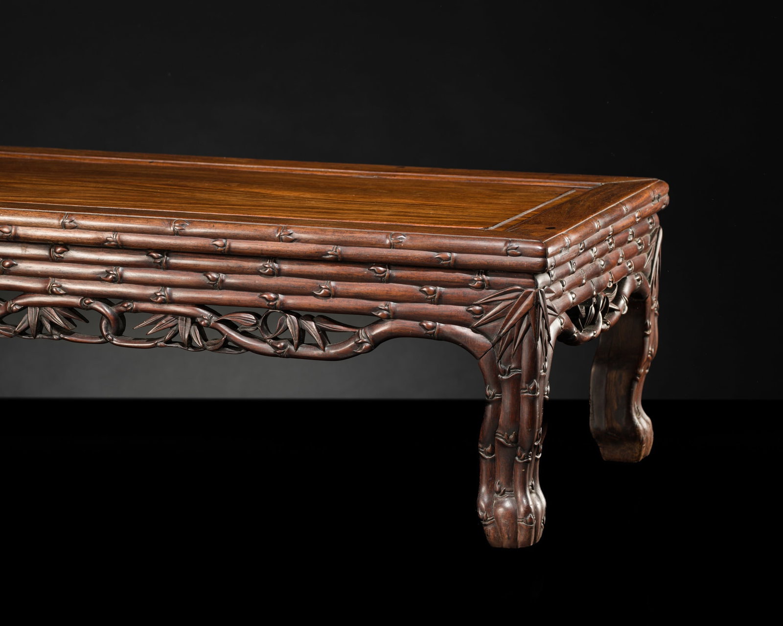 A HONGMU BAMBOO-MOTIF LOW TABLE, KANGZHUO, 17TH CENTURY: A HONGMU BAMBOO-MOTIF LOW TABLE, KANGZHUO, 17TH CENTURY This lot is from a single owner collection and is therefore offered without reserve China. Finely carved, the single panel top set within a wide