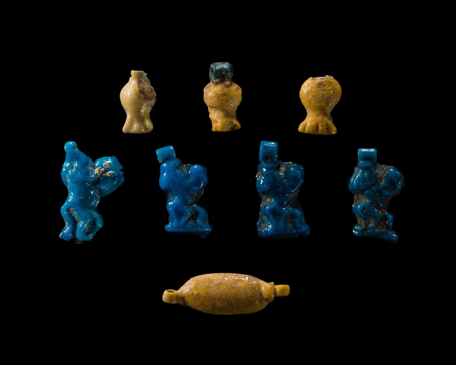 A GROUP OF FOUR TURQUOISE-BLUE FAIENCE 'BES' AMULETS AND FOUR YELLOW FAIENCE BEADS, NEW KINGDOM: A GROUP OF FOUR TURQUOISE-BLUE FAIENCE 'BES' AMULETS AND FOUR YELLOW FAIENCE BEADS, NEW KINGDOM This lot is from a single owner collection and is therefore offered without reserve Egypt, circa 1550-10