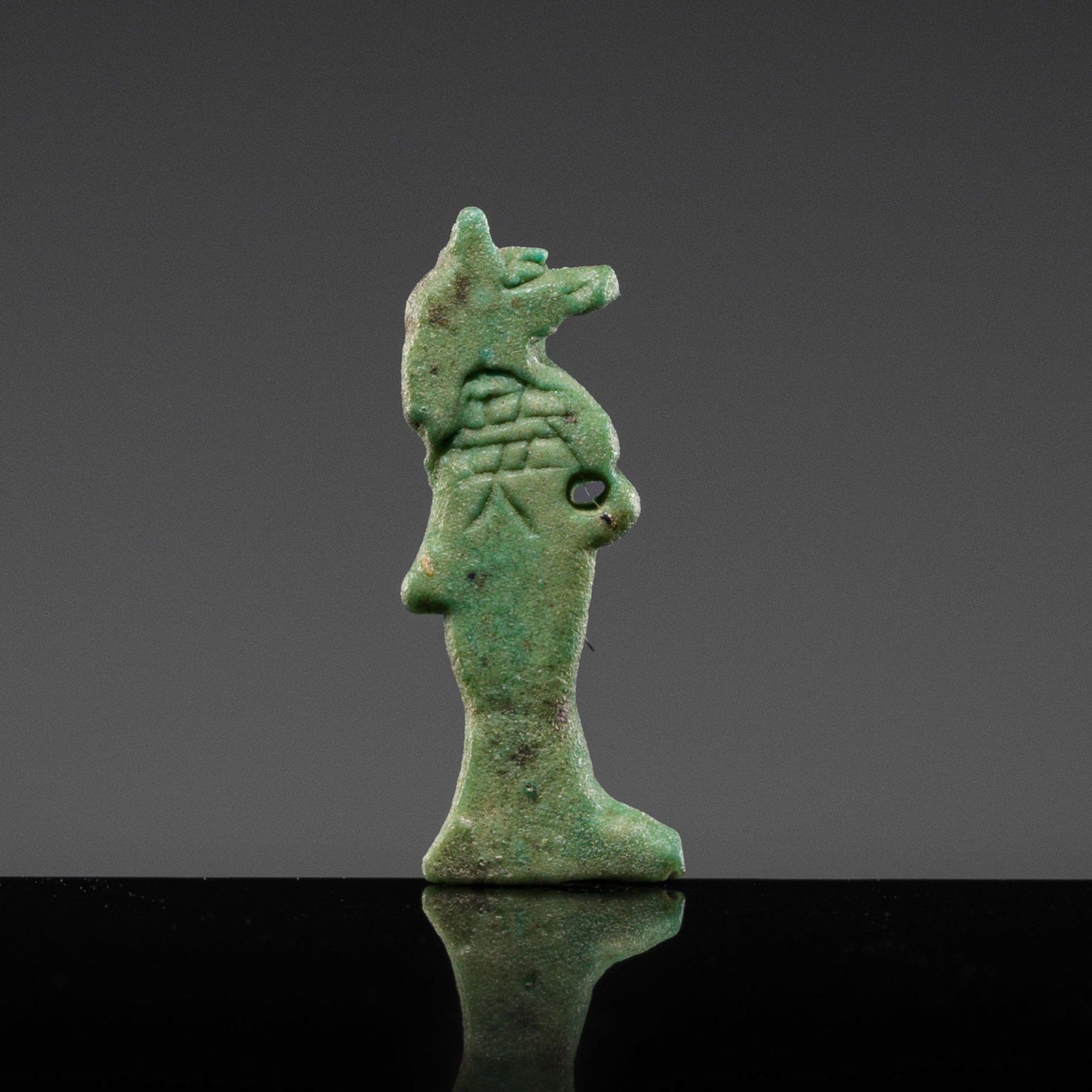 A RARE GREEN FAIENCE MINIATURE AMULET OF ANUBIS, LATE PERIOD-PTOLEMAIC PERIOD: A RARE GREEN FAIENCE MINIATURE AMULET OF ANUBIS, LATE PERIOD-PTOLEMAIC PERIOD This lot is from a single owner collection and is therefore offered without reserve Egypt, c. 664-30 BC. Of flattened form