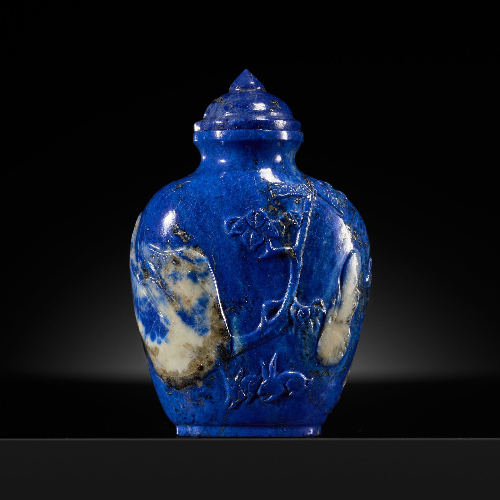A RARE LAPIS LAZULI SNUFF BOTTLE, 1760-1850: A RARE LAPIS LAZULI SNUFF BOTTLE, 1760-1850 China. Well hollowed and of flattened ovoid form, rising from an oval foot to a waisted neck with flat lip, the surface of the stone neatly carved in shallo