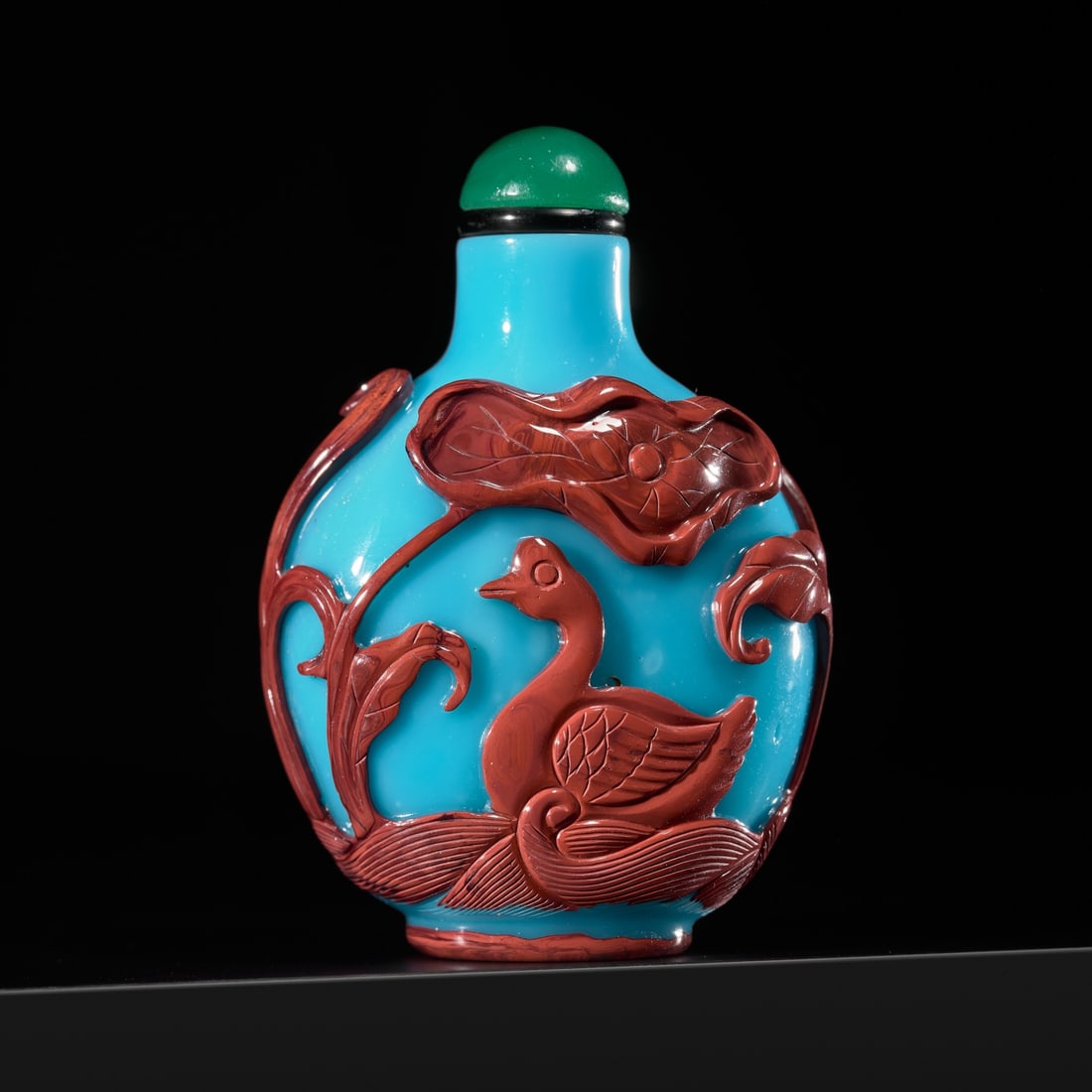 A PRISTINE CINNABAR OVERLAY 'GEESE IN LOTUS POND' TURQUOISE GLASS SNUFF BOTTLE, 1780-1850: A PRISTINE CINNABAR OVERLAY 'GEESE IN LOTUS POND' TURQUOISE GLASS SNUFF BOTTLE, 1780-1850 China. Of compressed globular form, rising from an oval foot to a cylindrical neck with flat lip, the opaque t