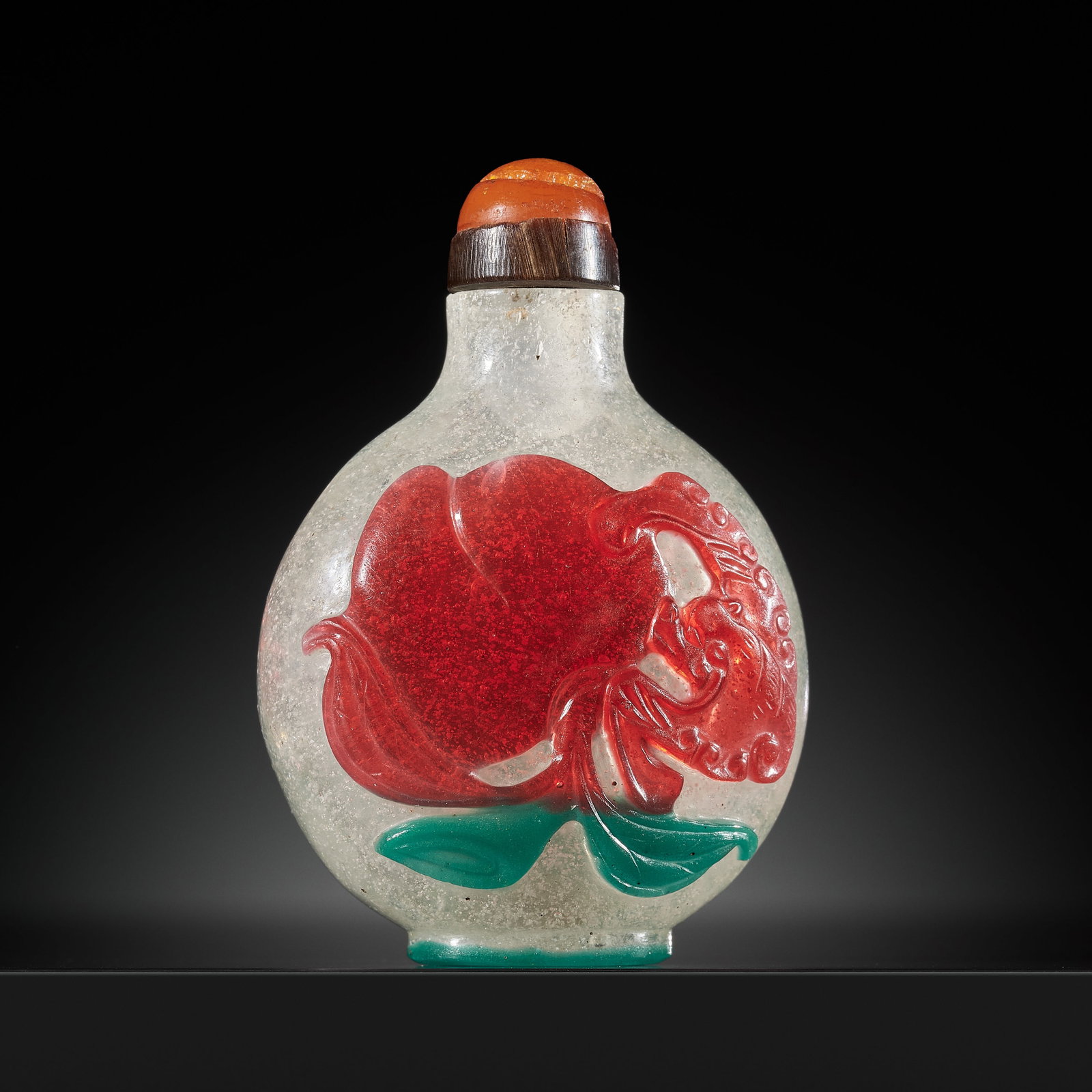 AN UNUSUAL RED AND GREEN OVERLAY 'PEACH AND LOTUS' SNOWFLAKE GLASS SNUFF BOTTLE, 1760-1840: AN UNUSUAL RED AND GREEN OVERLAY 'PEACH AND LOTUS' SNOWFLAKE GLASS SNUFF BOTTLE, 1760-1840 China, probably imperial glassworks, Beijing. Of compressed globular form, supported on a green lined oval fo