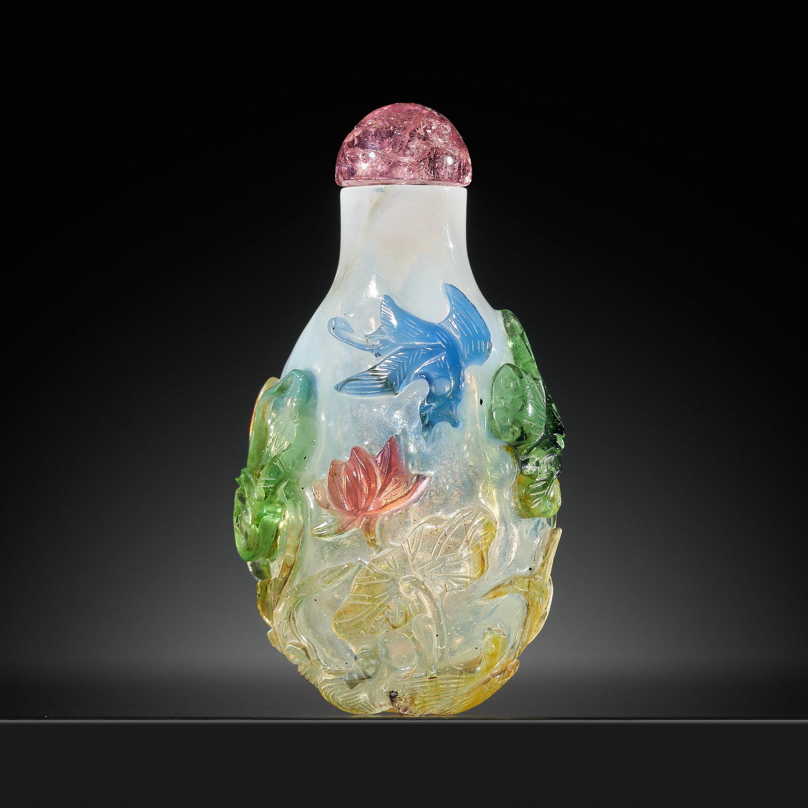 A FOUR-COLOR OVERLAY 'LOTUS POND' MILKY GLASS SNUFF BOTTLE, 19TH CENTURY: A FOUR-COLOR OVERLAY 'LOTUS POND' MILKY GLASS SNUFF BOTTLE, 19TH CENTURY China. Of ovoid form rising to a tubular neck with flat lip, carved through the sapphire-blue, pinkish-red, green, and swirled 