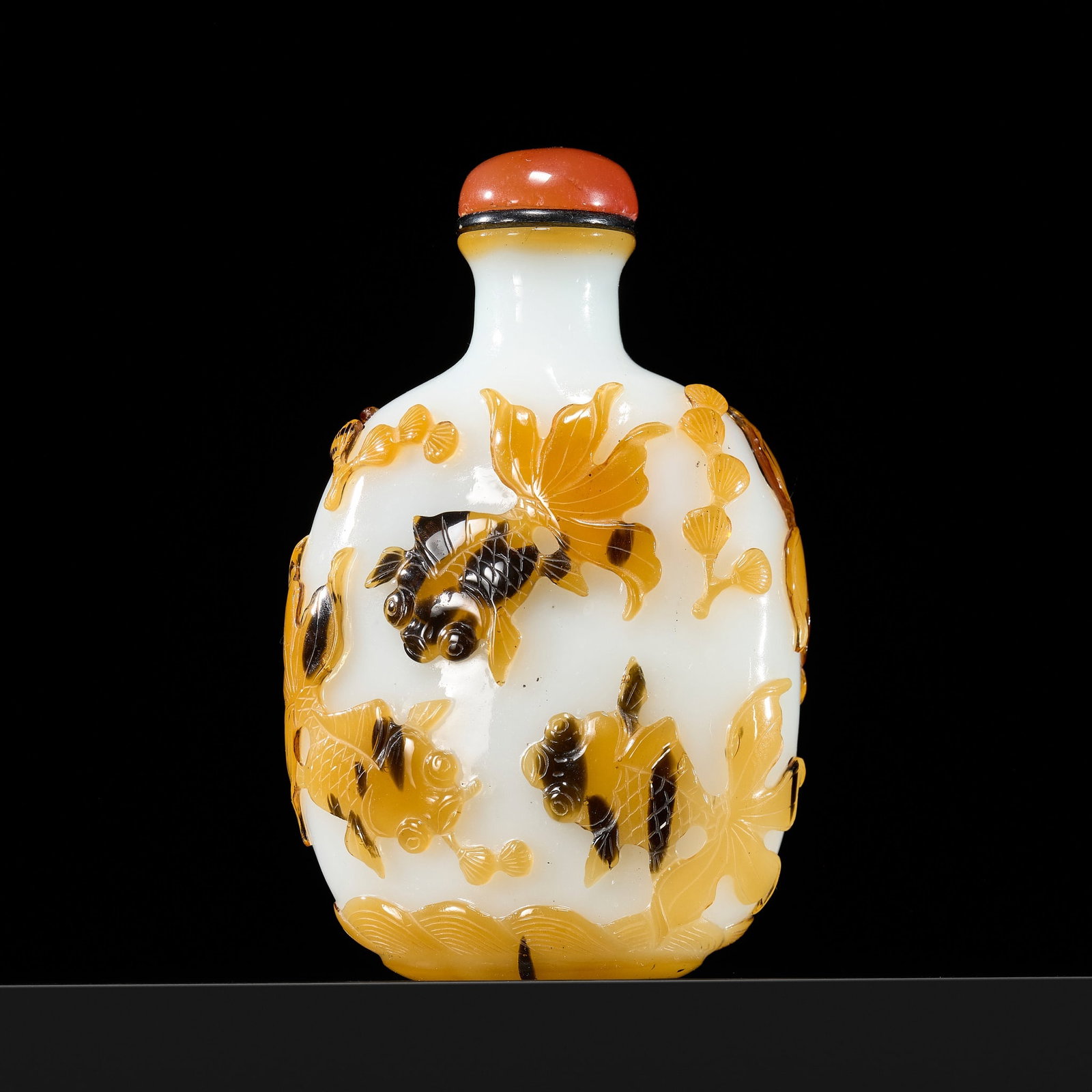 A YELLOW AND BLACK OVERLAY 'TELESCOPE EYE GOLDFISH' MILKY-WHITE GLASS SNUFF BOTTLE, CIRCA 1830-1930: A YELLOW AND BLACK OVERLAY 'TELESCOPE EYE GOLDFISH' MILKY-WHITE GLASS SNUFF BOTTLE, CIRCA 1830-1930 China. Of rounded rectangular form, supported on an oval foot and rising to a waisted neck with ever