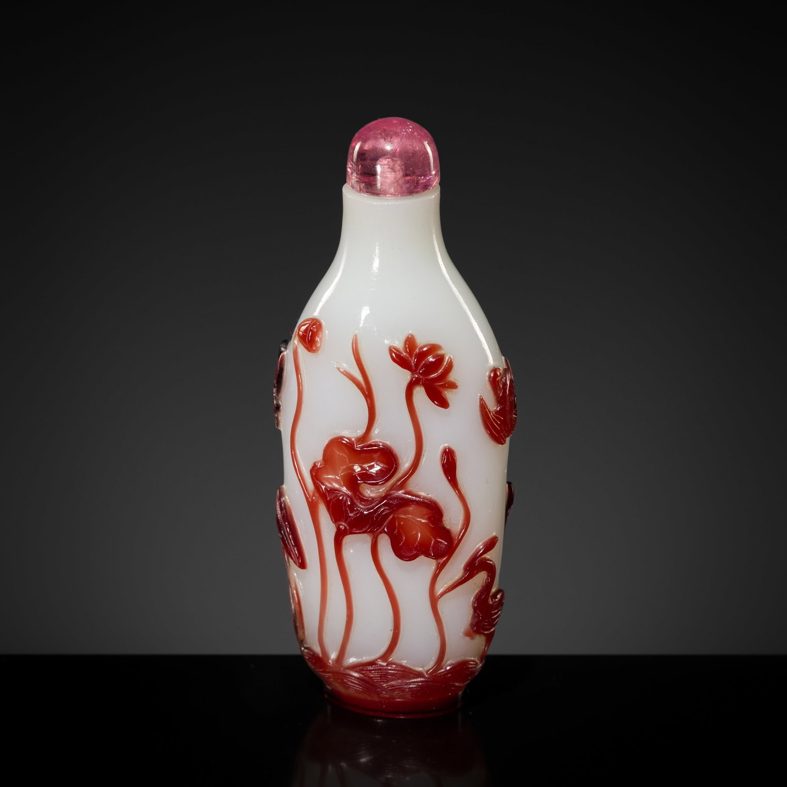 A RED-OVERLAY 'LOTUS POND' GLASS SNUFF BOTTLE, 1800-1860: A RED-OVERLAY 'LOTUS POND' GLASS SNUFF BOTTLE, 1800-1860 China. The bottle of elongated ovoid form, supported on an oval foot and rising to a cylindrical neck with flat lip, finely carved through the 