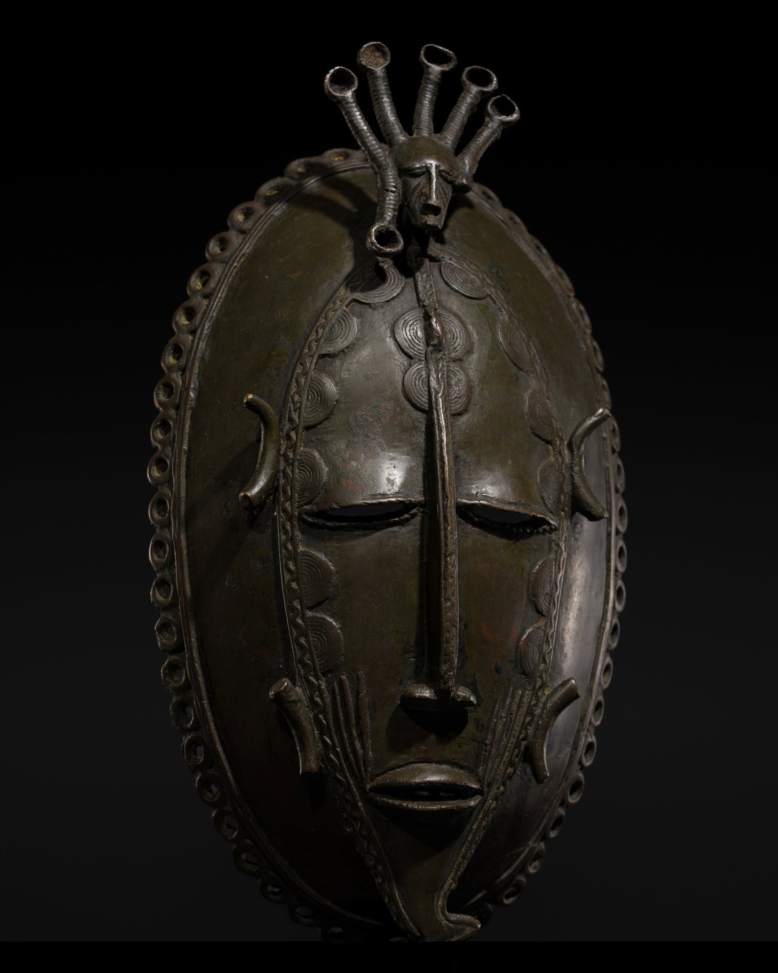 A DIULA-SENUFO BRONZE MASK, IVORY COAST, 20TH CENTURY: A DIULA-SENUFO BRONZE MASK, IVORY COAST, 20TH CENTURY This lot is from a single owner collection and is therefore offered without reserve The oval mask finely cast to depict a serene face with narrow 