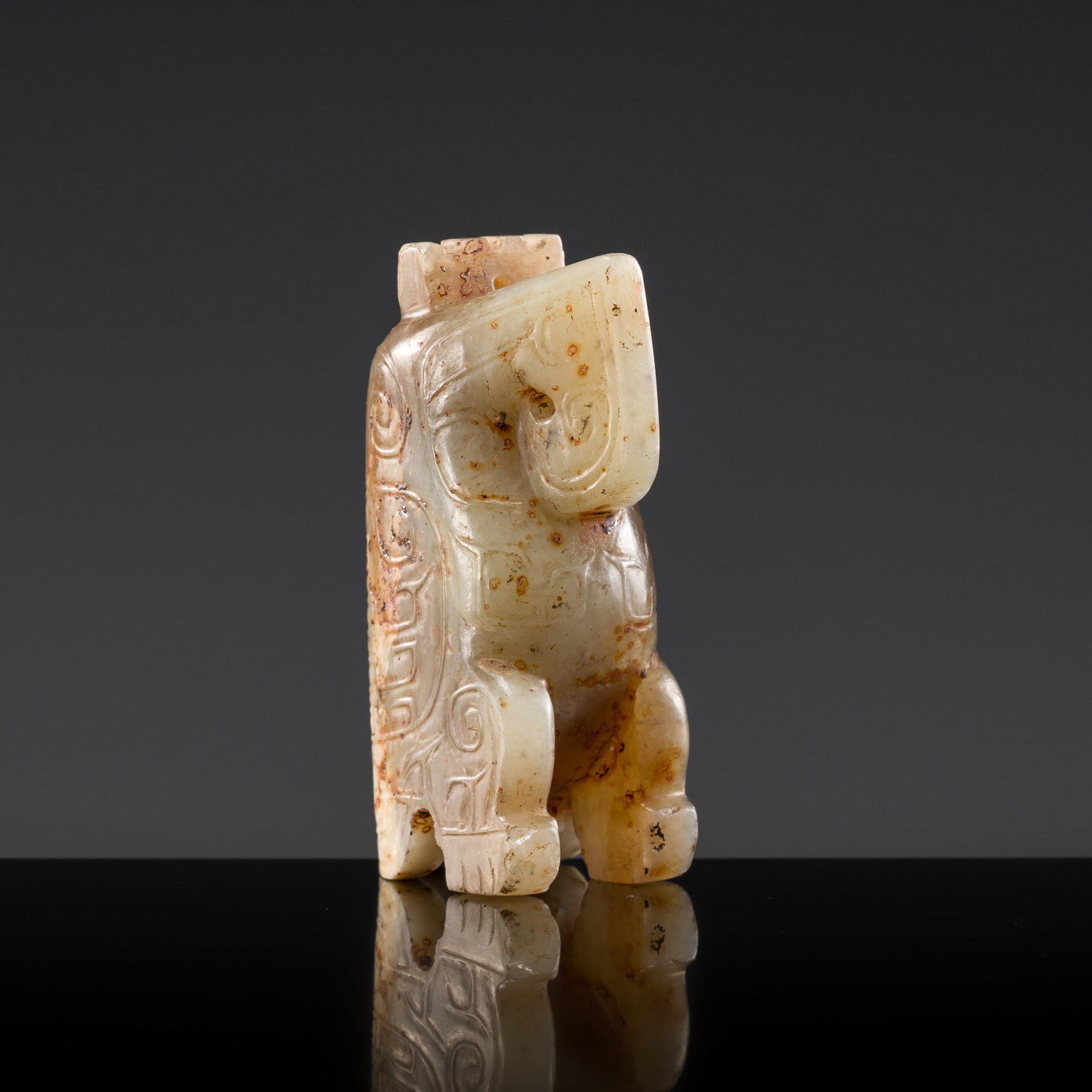 AN IMPORTANT PALE CELADON AND RUSSET JADE CARVING OF AN OWL, LATE SHANG DYNASTY: AN IMPORTANT PALE CELADON AND RUSSET JADE CARVING OF AN OWL, LATE SHANG DYNASTY China, c. 13th-11th century BC. Finely carved in the round, the avian creature depicted crouching on its feet and tail, 