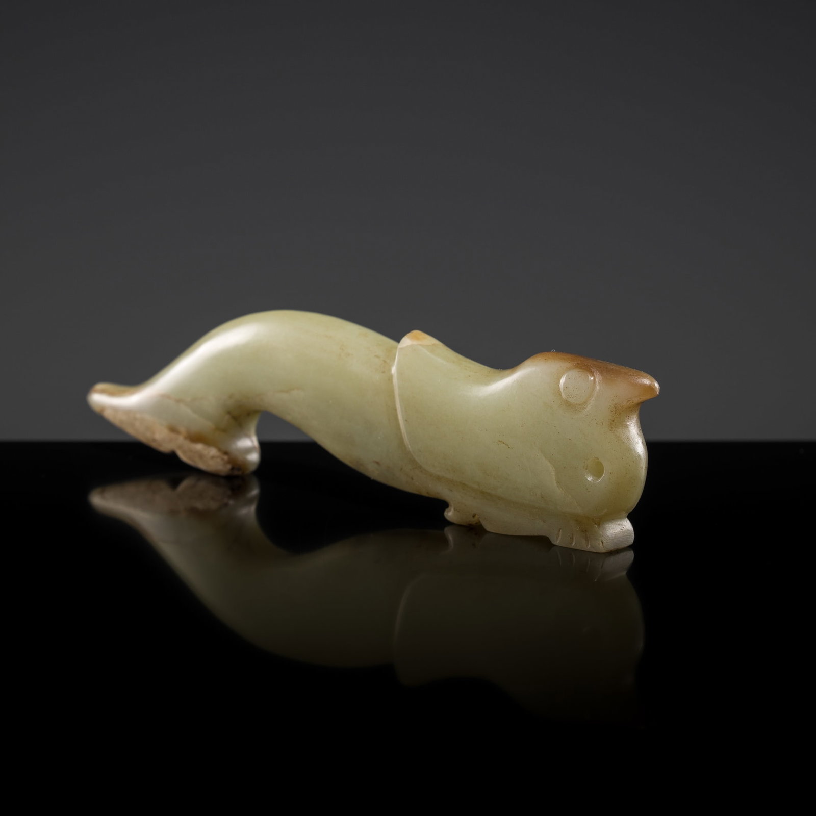 A YELLOWISH-GREEN AND RUSSET JADE 'BIRD' PENDANT, LATE SHANG TO WESTERN ZHOU DYNASTY: A YELLOWISH-GREEN AND RUSSET JADE 'BIRD' PENDANT, LATE SHANG TO WESTERN ZHOU DYNASTY China, c. 1050-770 BC. Finely carved in a flattened form, the avian creature depicted with an elongated, slightly c