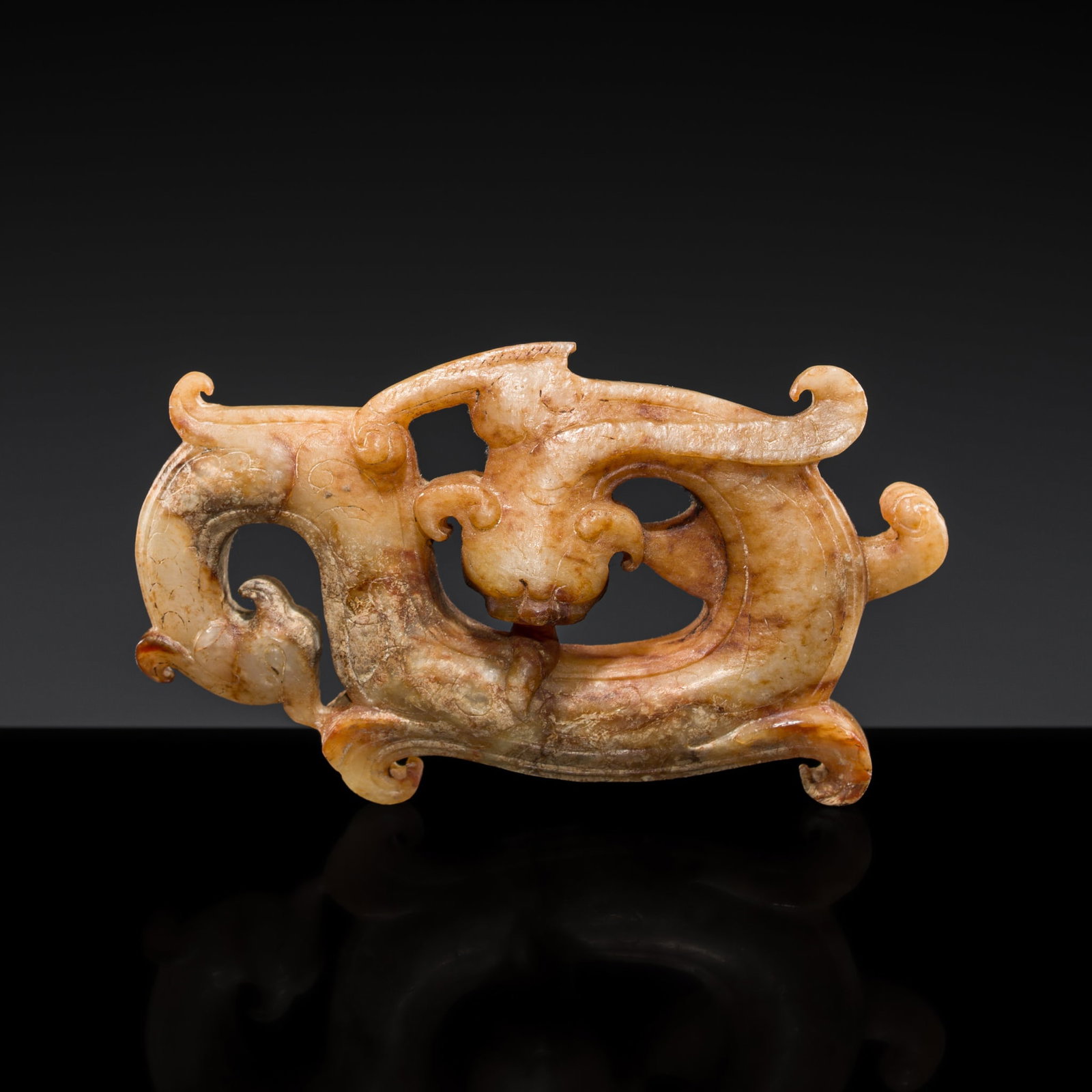 A PALE CELADON AND RUSSET JADE 'DRAGON AND PHOENIX' PENDANT, WESTERN HAN DYNASTY: A PALE CELADON AND RUSSET JADE 'DRAGON AND PHOENIX' PENDANT, WESTERN HAN DYNASTY China, 206 BC-9 AD. Finely carved, the dragon coiling upon itself, its sinuous contour embellished with scrolling motif