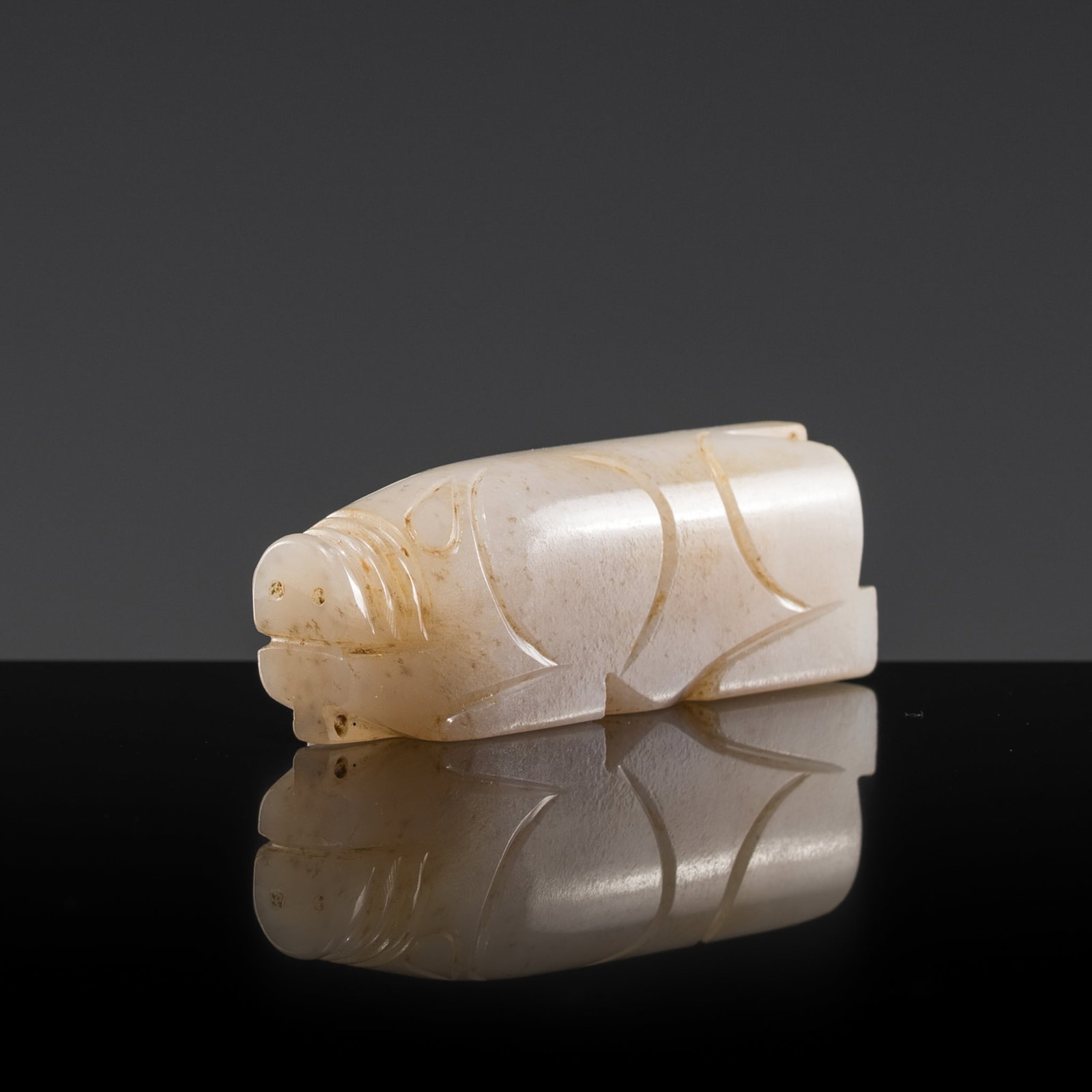 A WHITE JADE CARVING OF A PIG, HAN DYNASTY: † A WHITE JADE CARVING OF A PIG, HAN DYNASTY Expert authentication: Dr. Gu Fang has examined the present lot and confirms its authenticity and the dating above, noting the style of cutting, work