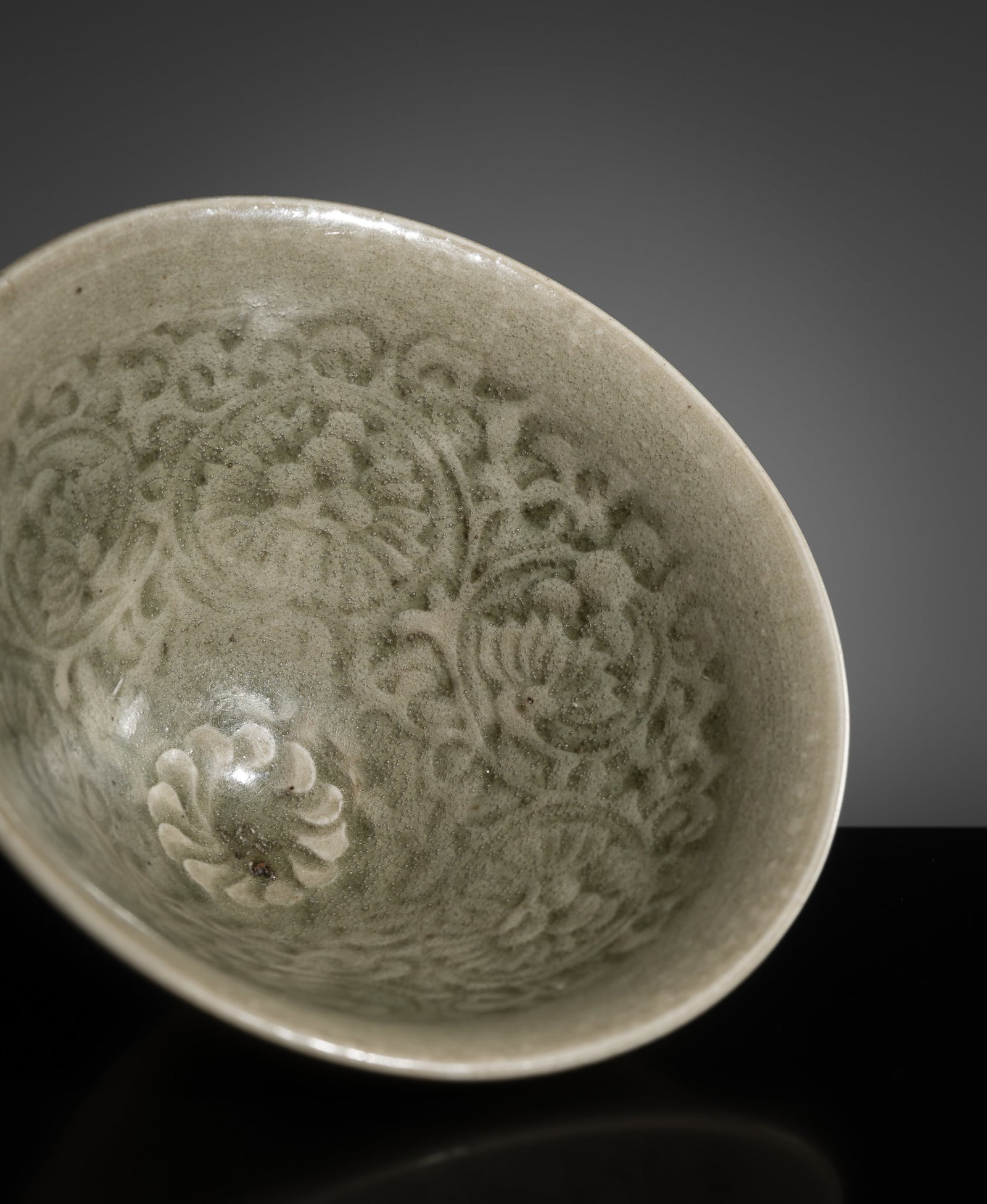 A MOLDED YAOZHOU CELADON 'CHRYSANTHEMUM' BOWL, NORTHERN SONG DYNASTY: A MOLDED YAOZHOU CELADON 'CHRYSANTHEMUM' BOWL, NORTHERN SONG DYNASTY China, 960-1127. Of conical form with an everted rim, the interior crisply molded with three stylized flowers in full bloom borne o