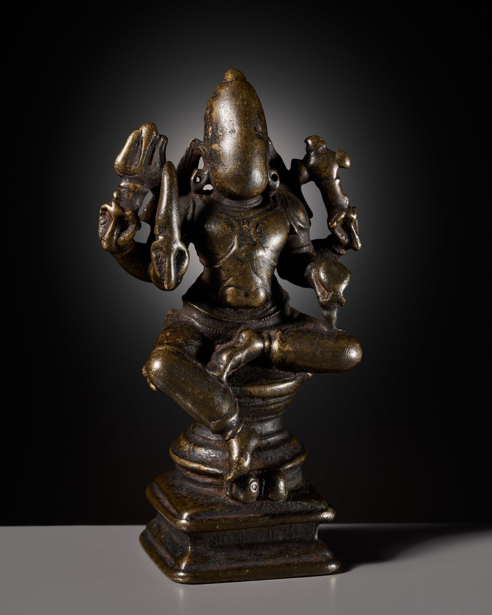 A BRONZE FIGURE OF BHAIRAVA, NORTHERN DECCAN, 17TH-18TH CENTURY: A BRONZE FIGURE OF BHAIRAVA, NORTHERN DECCAN, 17TH-18TH CENTURY South India. Finely cast, the four-armed wrathful deity seated in lalitasana upon a waisted pedestal raised on a tiered rectangular plin