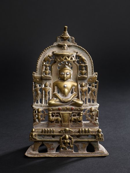 ALTAR WITH TIRTHANKARA SEATED ON THRONE: Brass bronze, some silver. India, Gujarat, dated 1369 An early small Jain altar with the depiction of a tirthankara (one of the 24 teachers in Jainism), shown seated in dhyanasana and dhyana mudra on 
