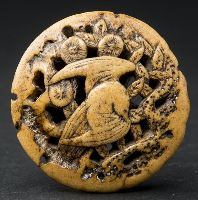 RYUSA NETSUKE: Horn. Japan, 19th century This attractive open-worked ryusa netsuke in round manju or rather button form depicts a bird perched in a tree. The other side is somewhat rustic and presents a strong horn 