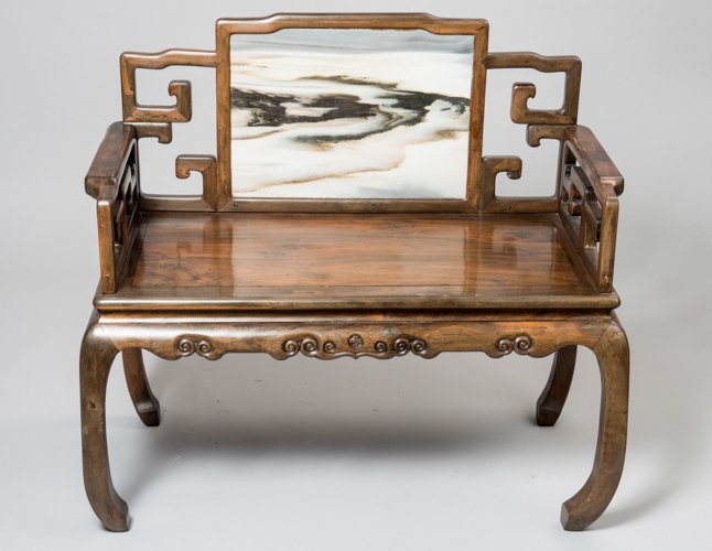 BENCH WITH BACK- AND ARMREST AND MARBLE-PLATE: Fine wood, marble. China, late Qing, approx. 1900 Four inwardly curved legs, smooth seating surface, beneath it all around a carved relief with spirals and in the middle of each side, a motif with fou