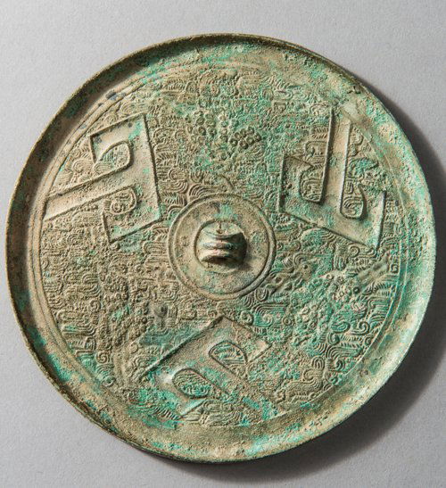 A CIRCULAR MIRROR WITH SHAN MOTIFS: Bronze. China, in the style of the Warring States Period The mirror cast with a central triple-fluted knob enclosed by an even circular section interspersed with three inclined large â€œTâ€ â�